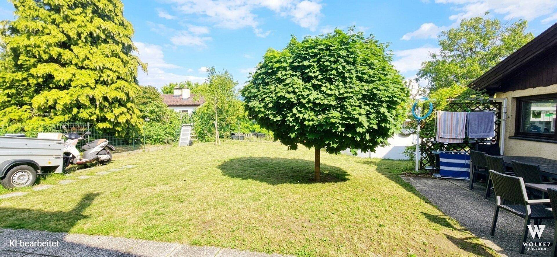 Weitläufiger Gartenbereich mit Rasen, schattenspendendem Baum und Terrasse für entspannte Stunden.