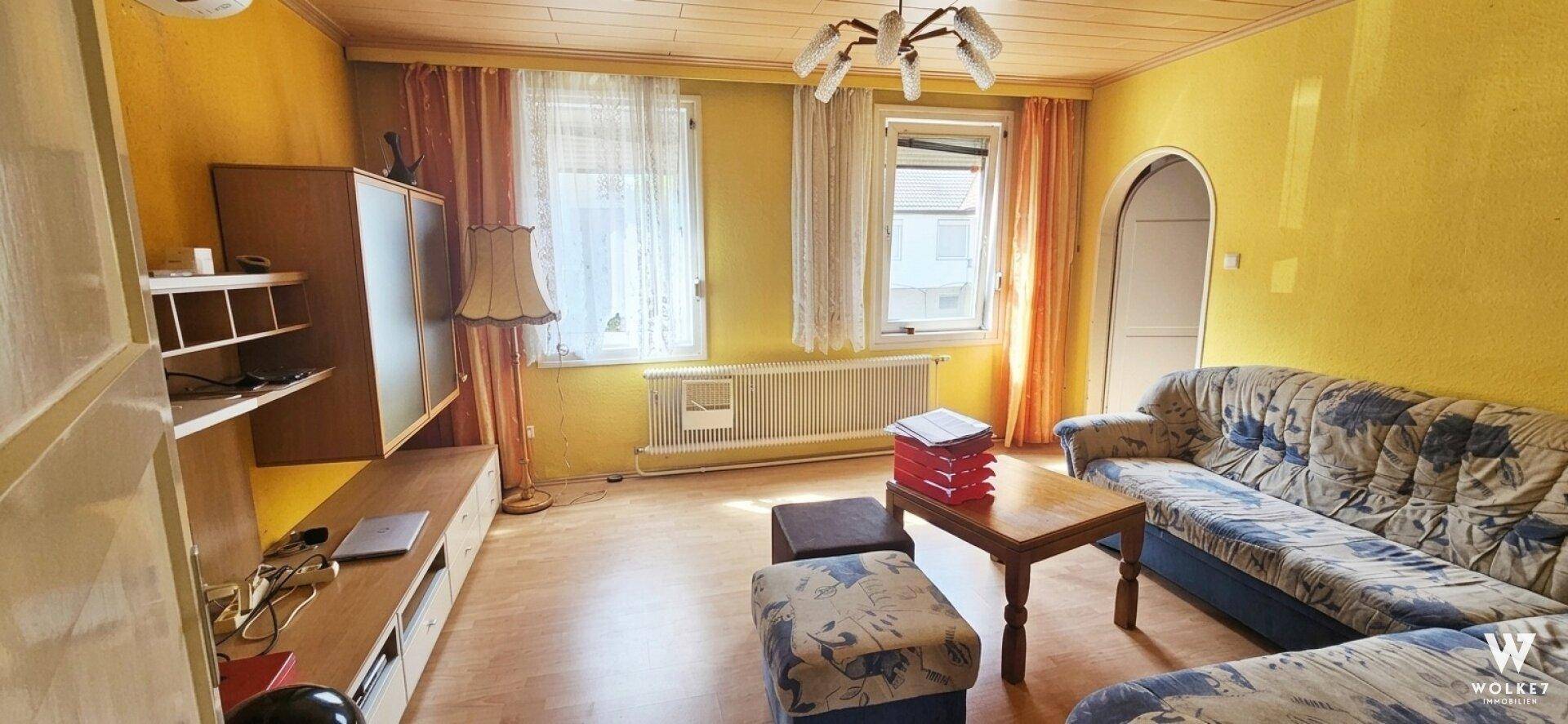 Gemütliches Wohnzimmer mit gelben Wänden, Holzdecke und traditionellen Möbeln.