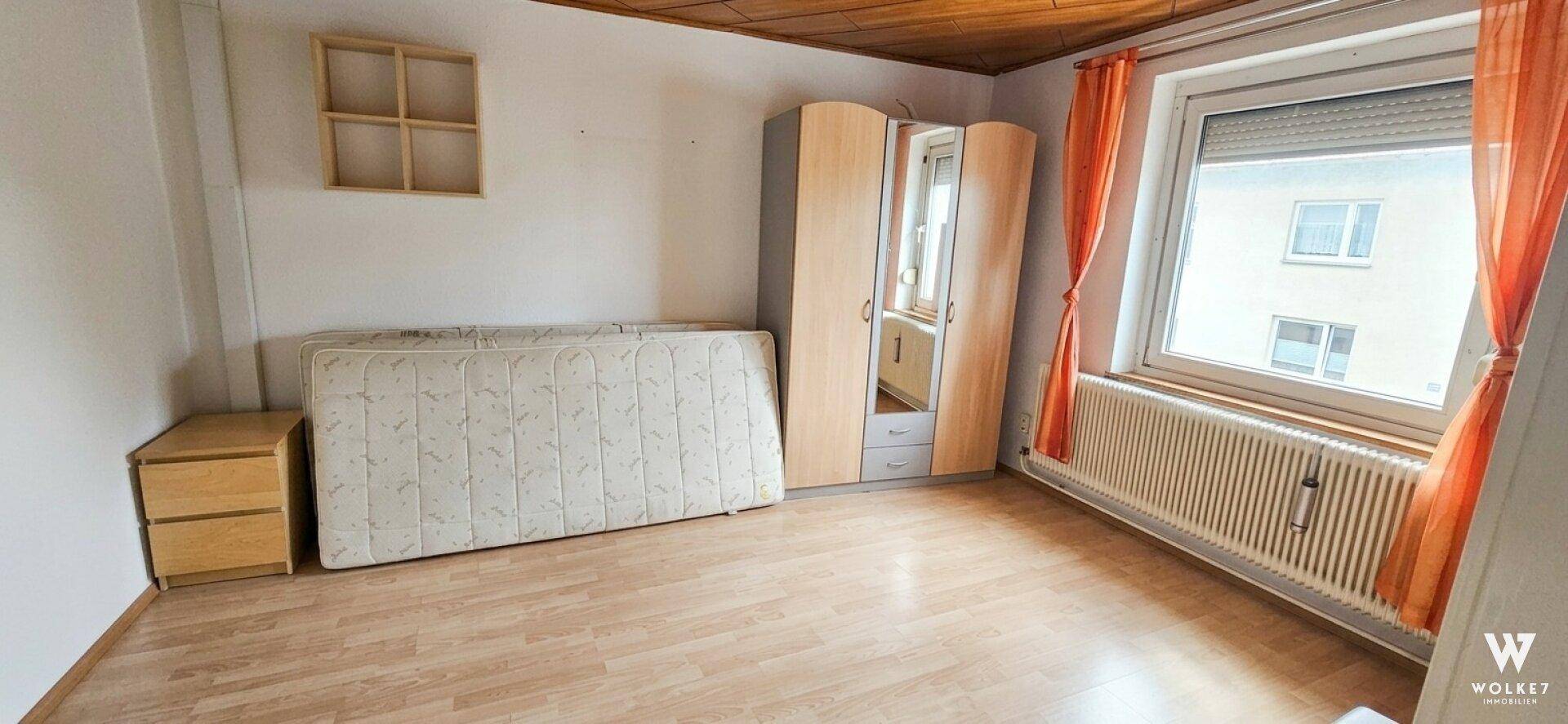 Schlafzimmer mit Holzdecke, Laminatboden und großem Fenster, unmöbliert.