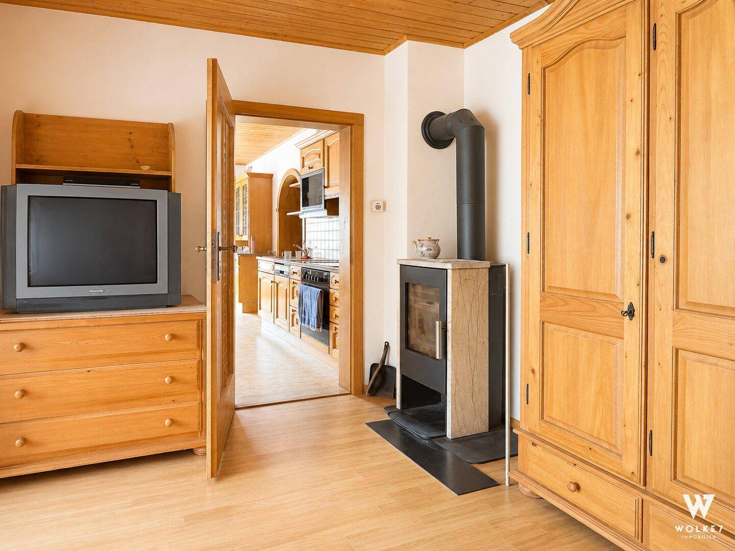 Gemütlicher Wohnbereich mit Holzboden, Kaminofen und Zugang zur Küche.