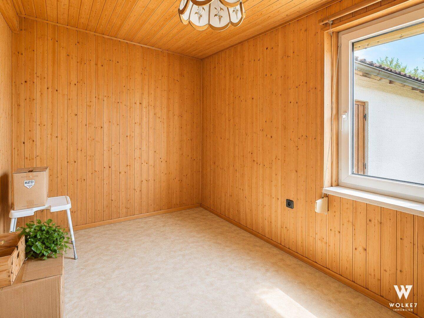 Raum mit Holzvertäfelung, Teppichboden und Fenster.