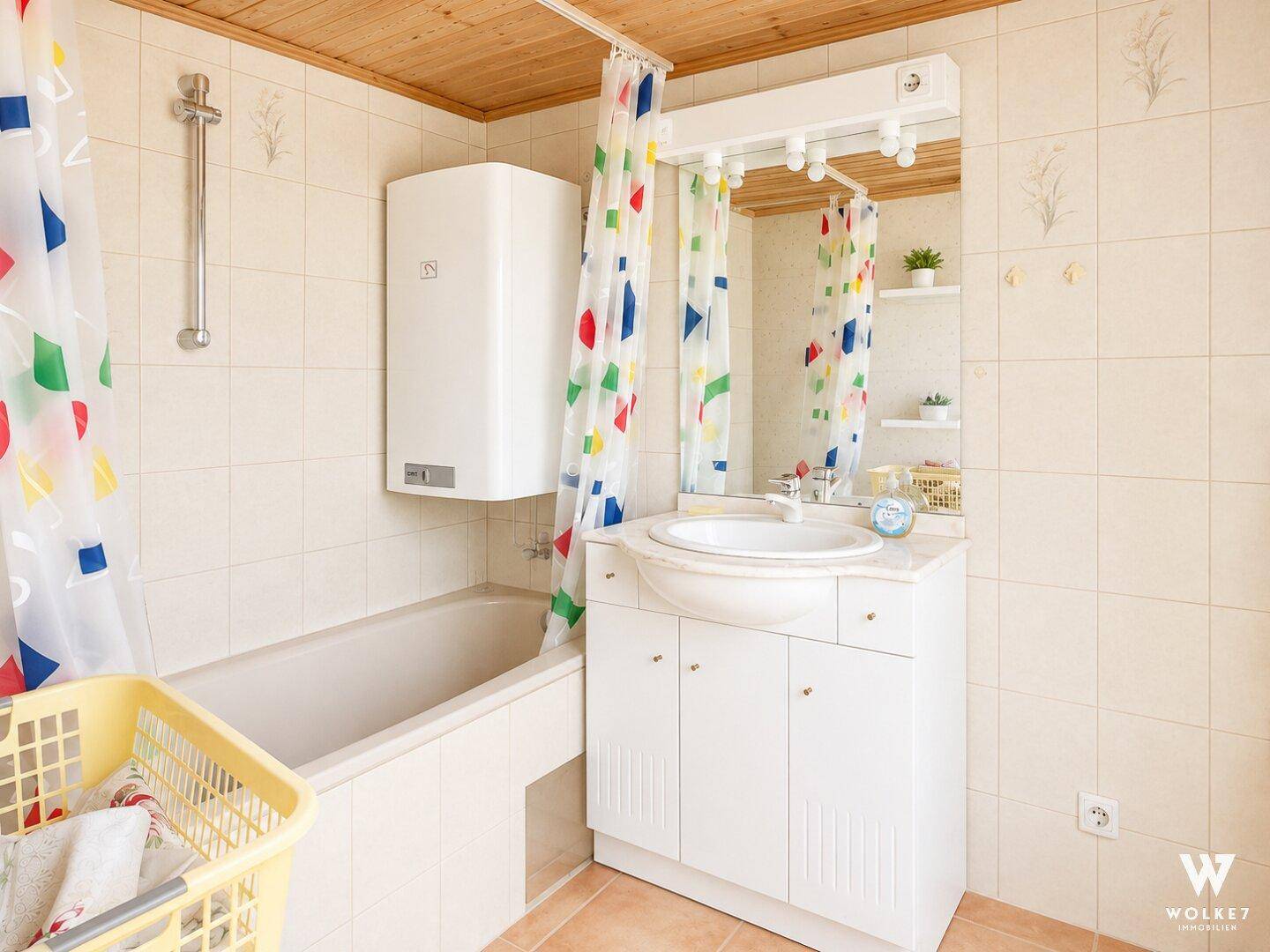 Badezimmer mit Badewanne, Waschbecken und bunten Duschvorhängen.