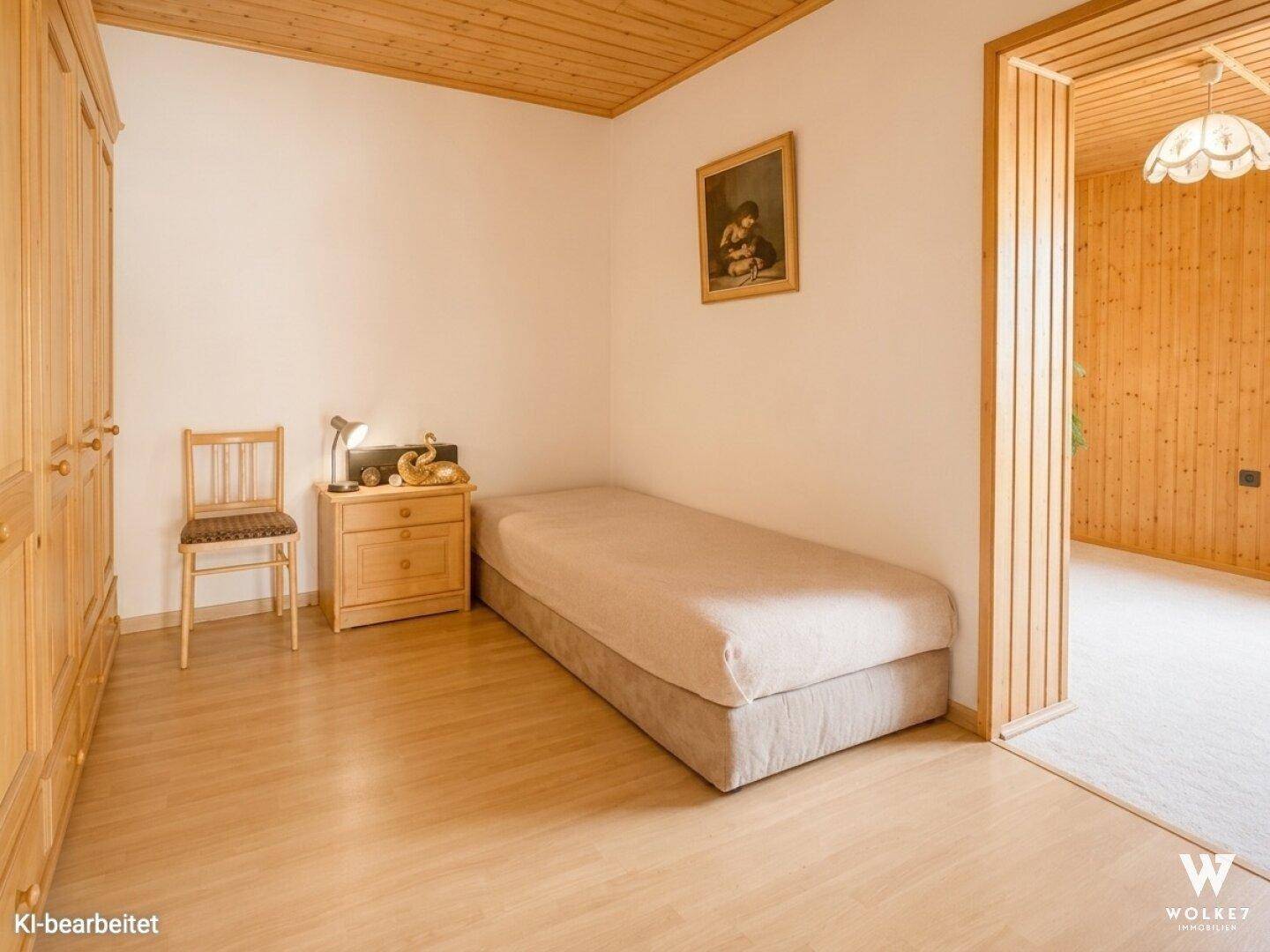 Schlafzimmer mit Einzelbett, Holzschrank und Holzboden.