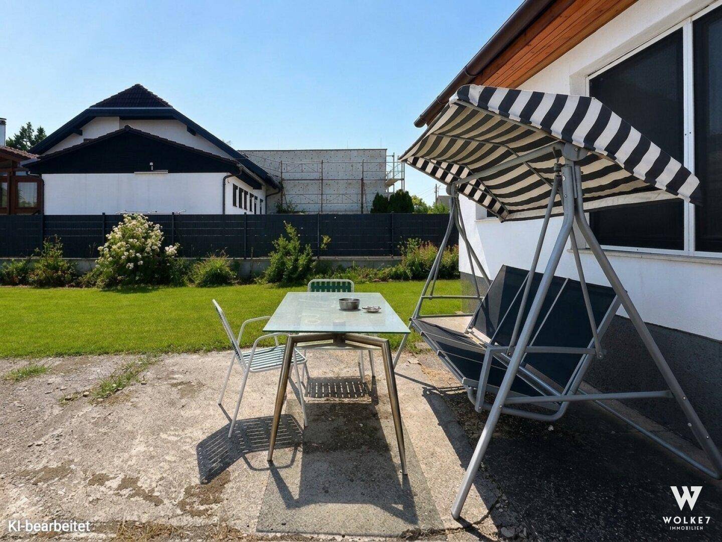Terrasse mit Gartentisch, Schaukel und Blick auf den Garten.