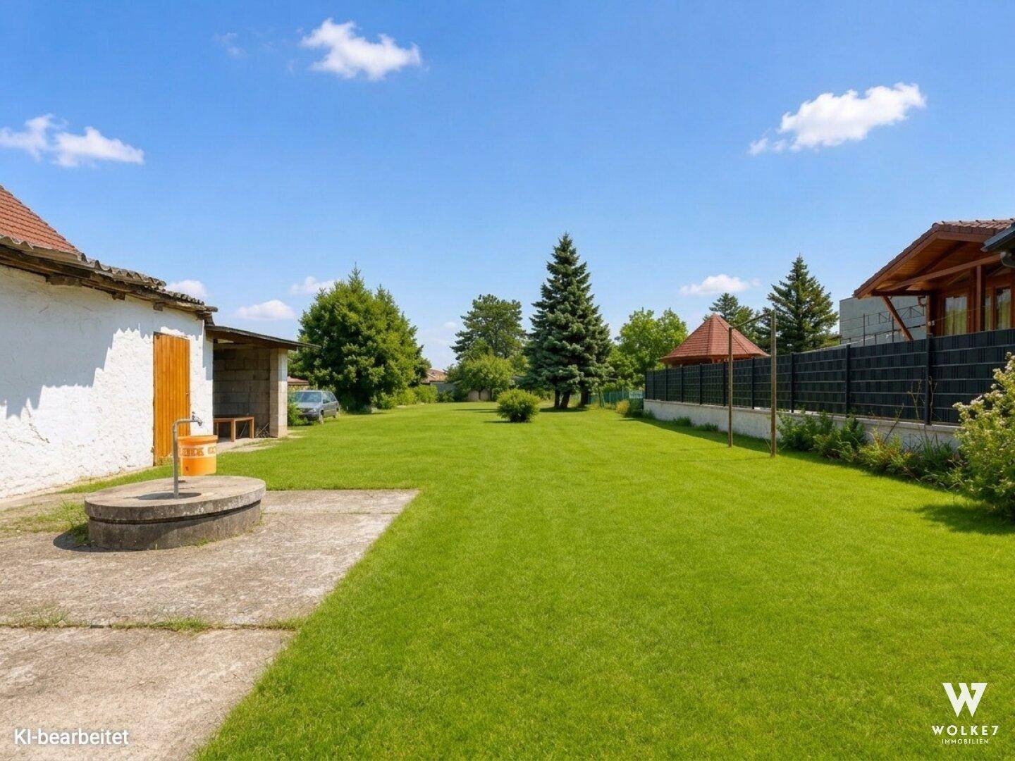 Weitläufiger Gartenbereich mit Rasen, Betonflächen und einem Brunnen, umgeben von Bäumen.