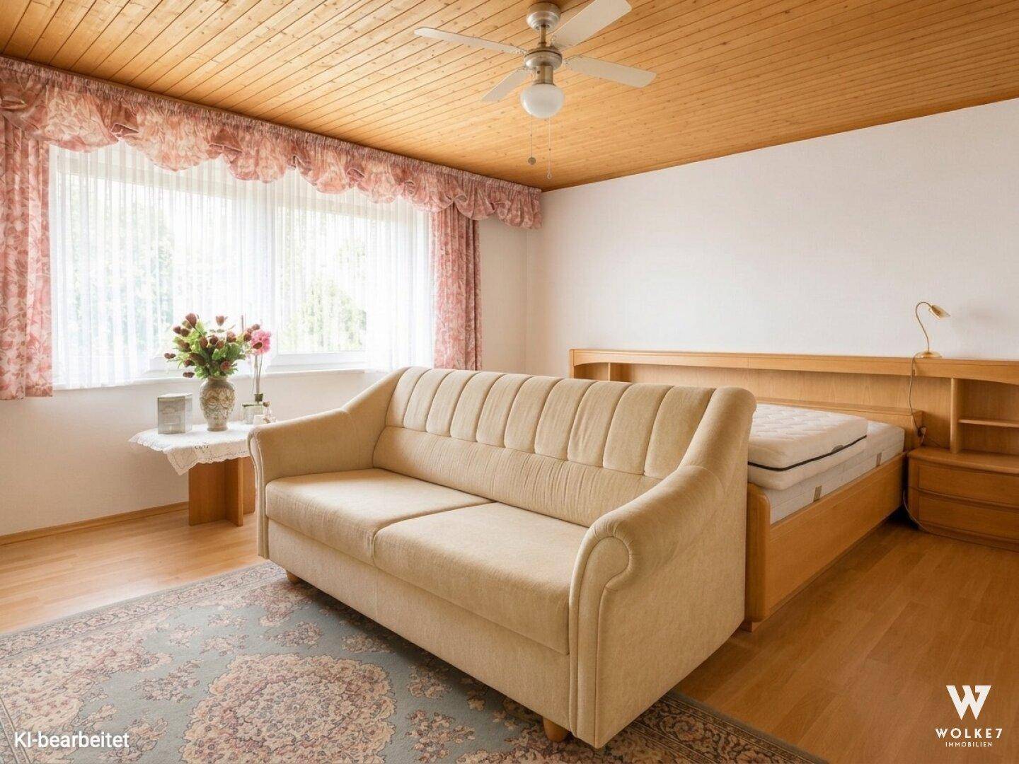 Schlafzimmer mit Holzdecke, beigem Sofa und Fenster mit Vorhängen.