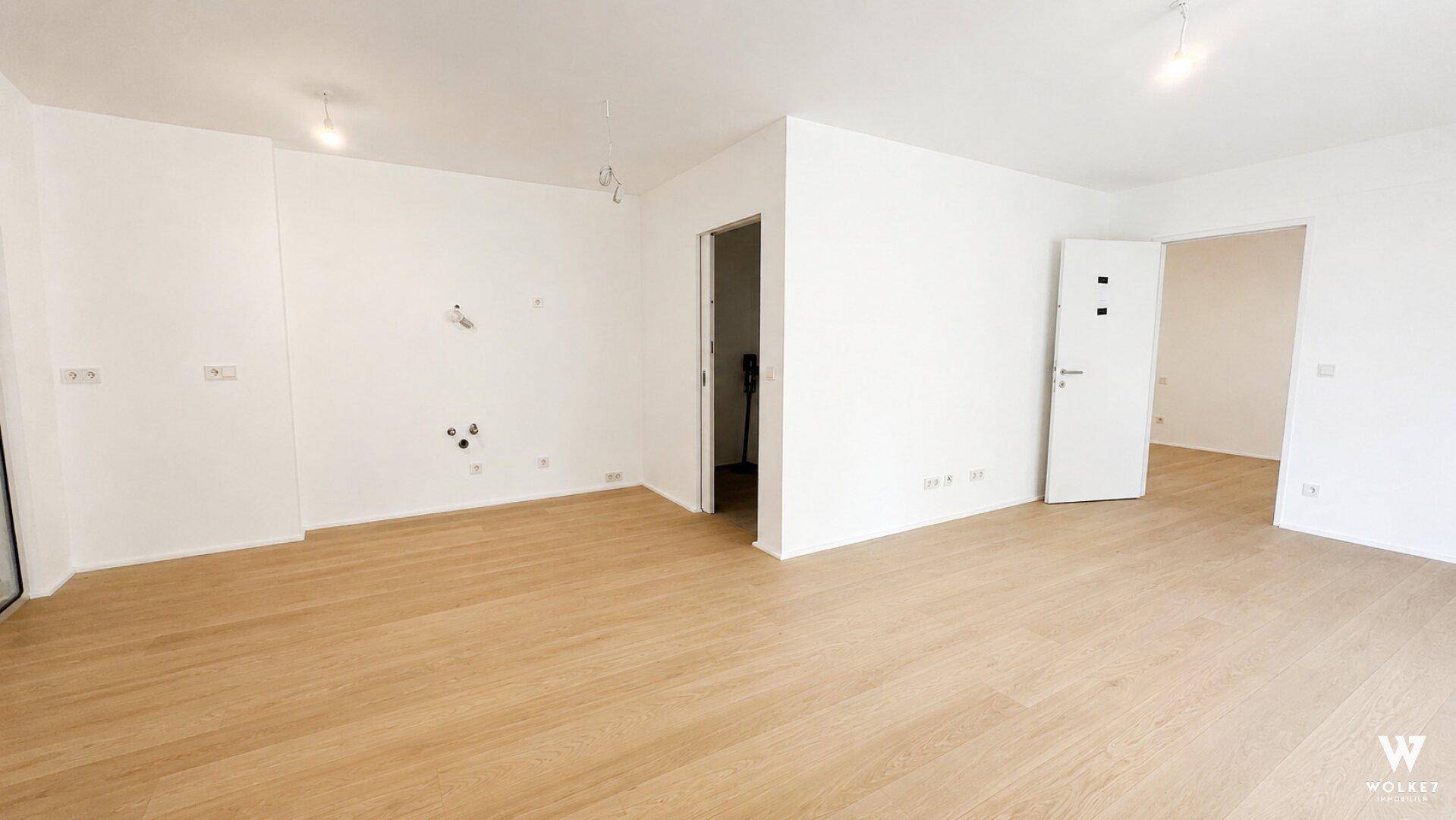 Unmöblierter, heller Innenraum mit Holzboden und weißen Wänden, bereit zur individuellen Gestaltung.