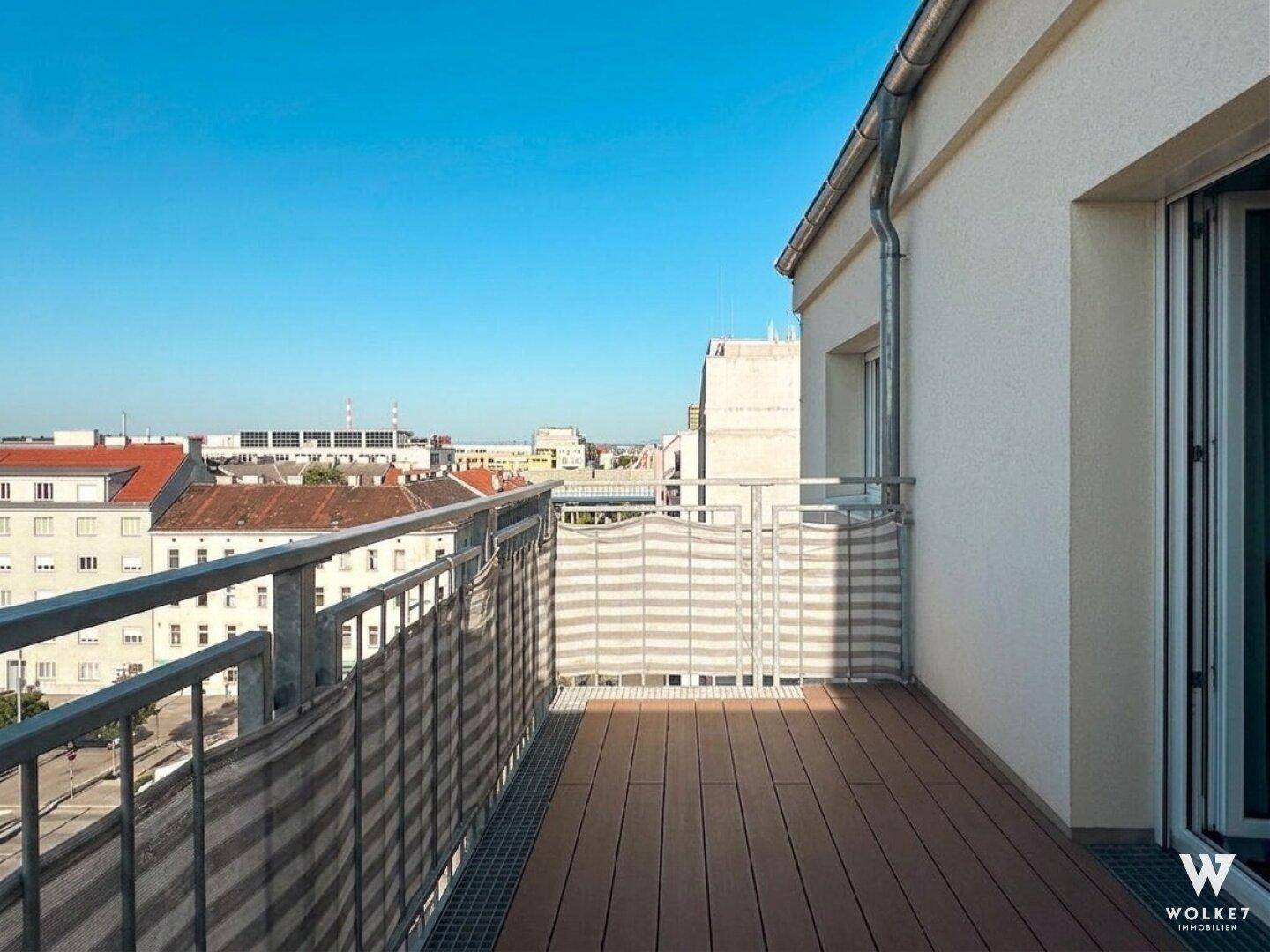 Geräumiger Balkon mit Holzboden und Metallgeländer bietet einen weiten Blick über die Stadt.