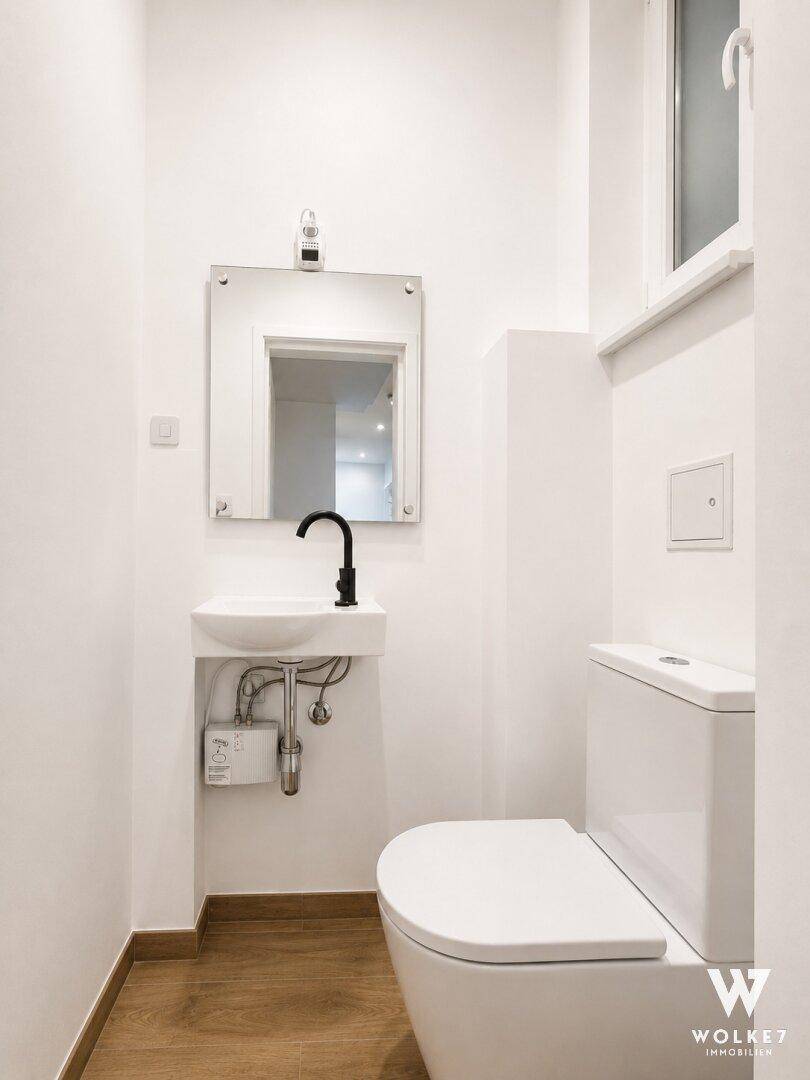 Kleines Gäste-WC mit modernem WC, Waschbecken und Fenster, hell und funktional gestaltet.