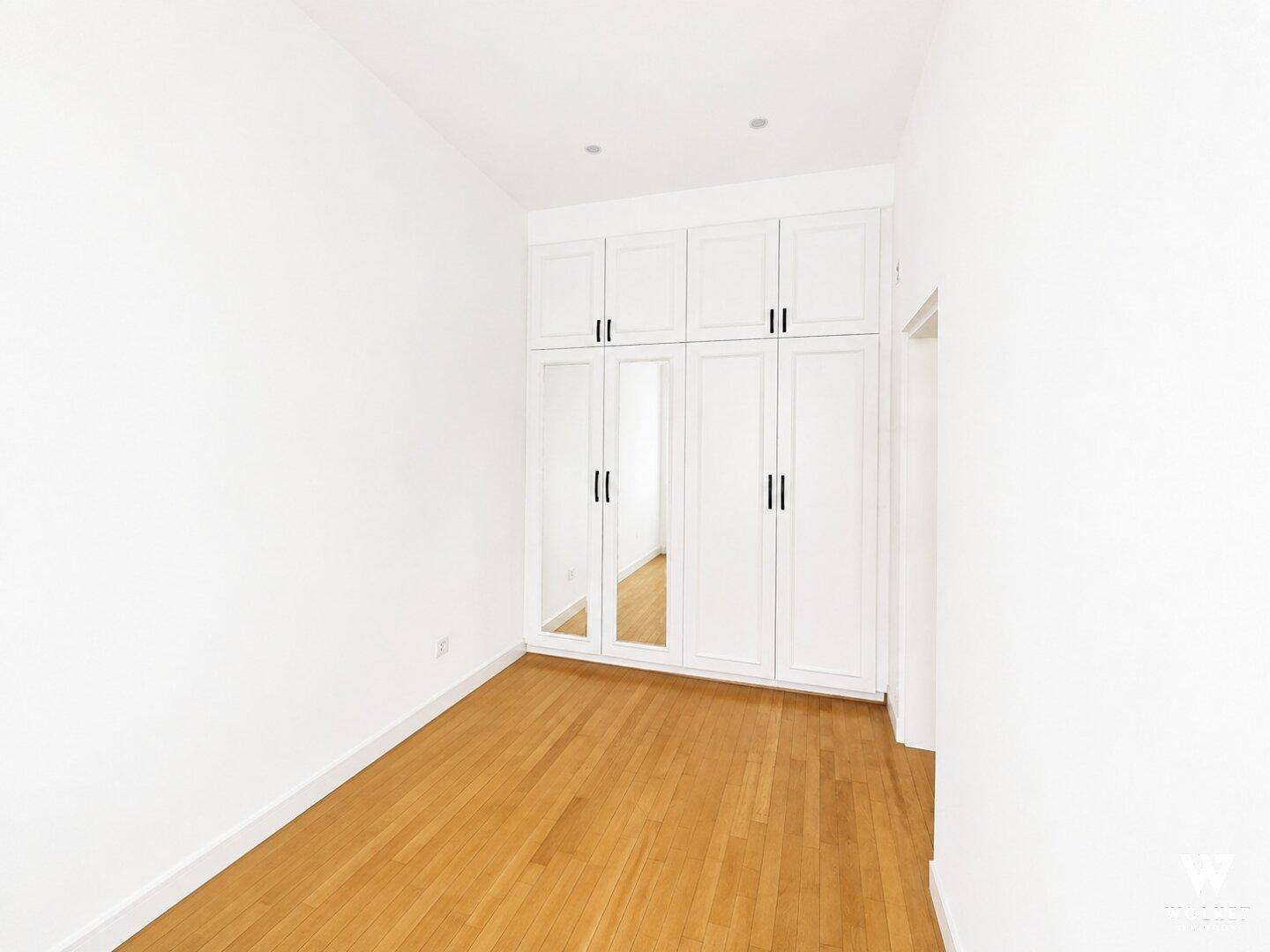 Leeres Zimmer mit praktischen Einbauschränken und Spiegeltüren, bietet viel Stauraum.