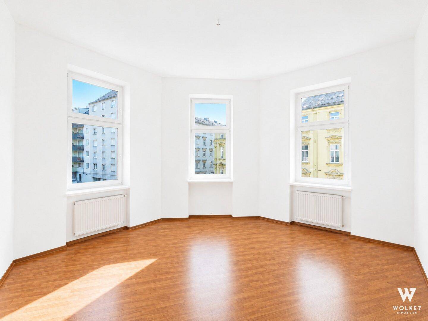 Helles, leeres Schlafzimmer mit Parkettboden und Erkerfenstern, ideal für individuelle Gestaltung.