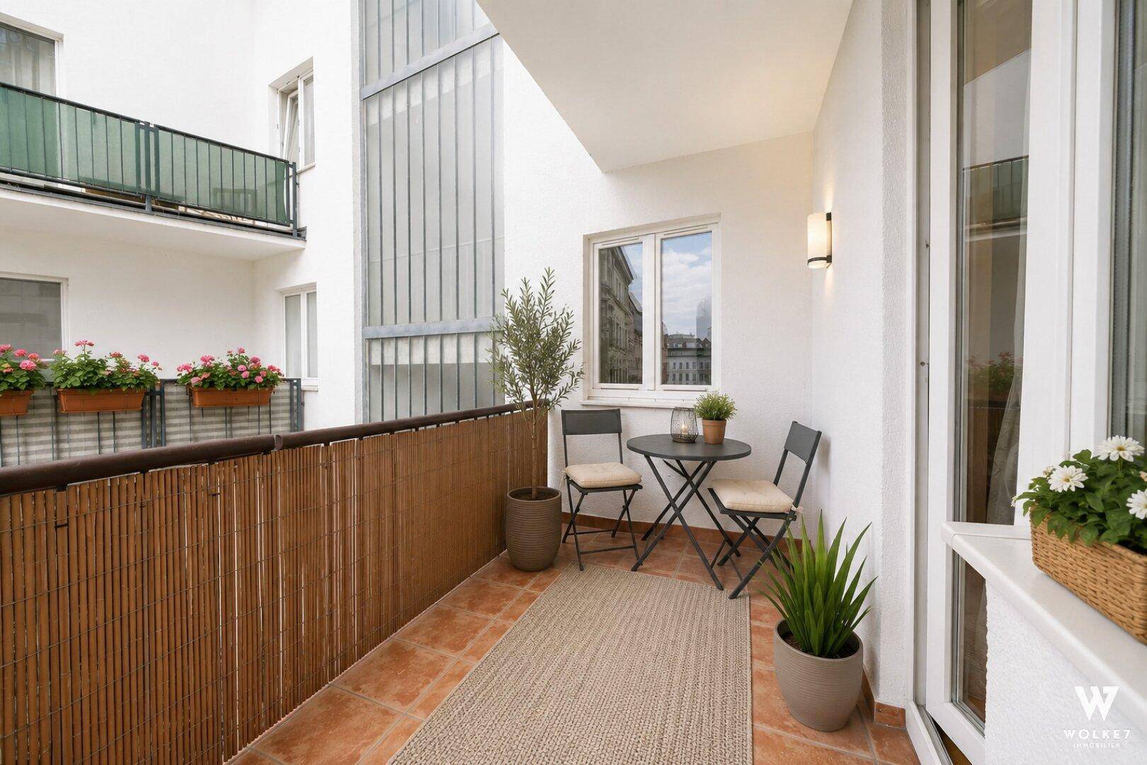 Gemütlicher Balkon mit Terrakottafliesen, Sitzgelegenheiten und Pflanzen, ideal für entspannte Stunden im Freien.