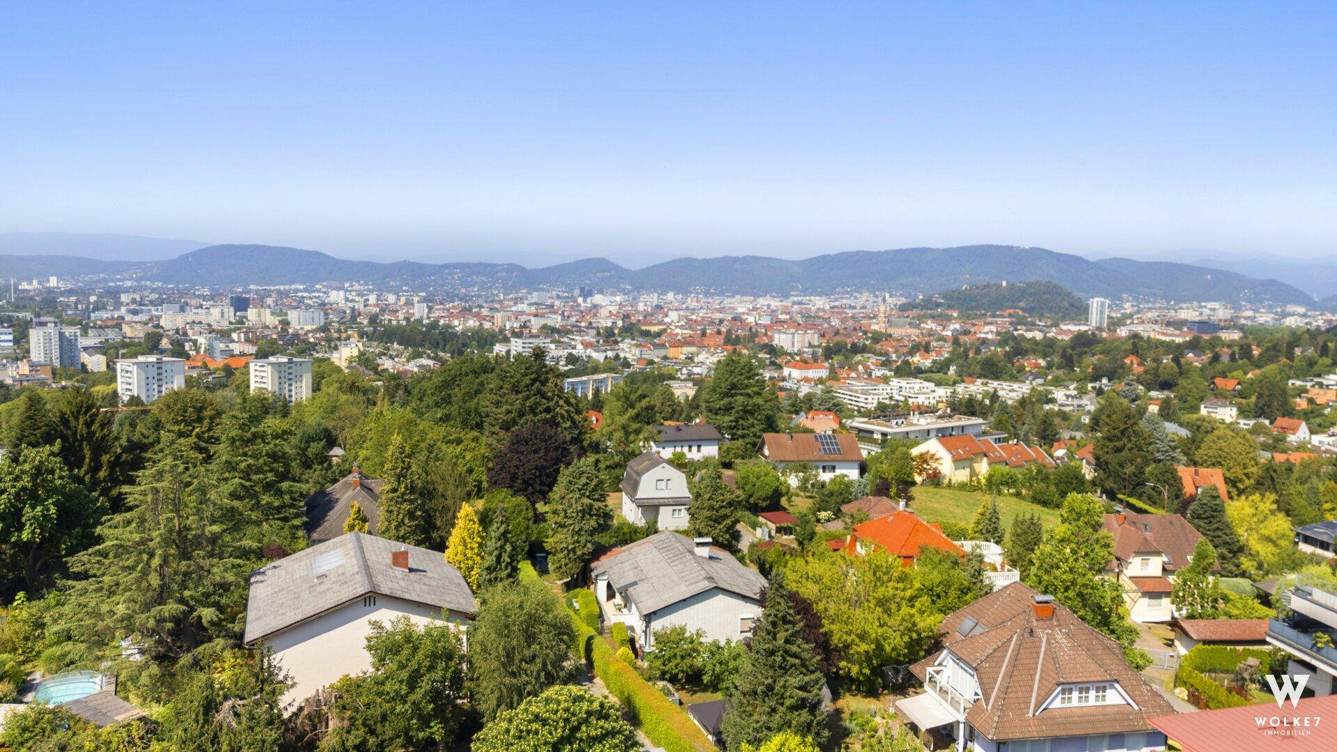 Panoramablick über die Stadt und die umliegende grüne Hügellandschaft.
