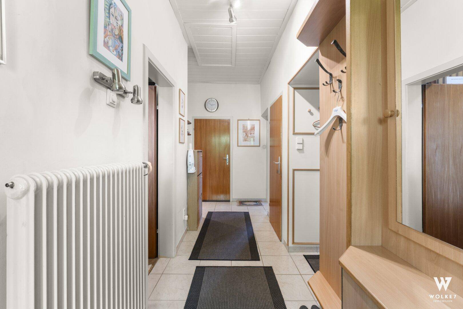 Heller Flur mit Fliesenboden und Garderobe, der zu weiteren Räumen führt.