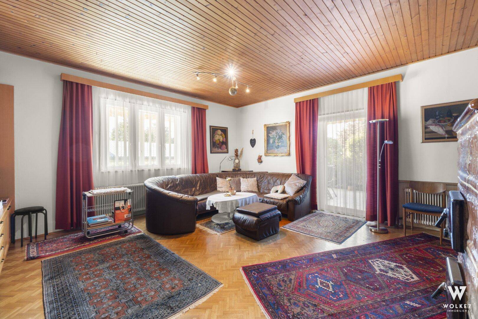 Helles Wohnzimmer mit Holzbalkendecke, bequemen Sofas und großen Fenstern.