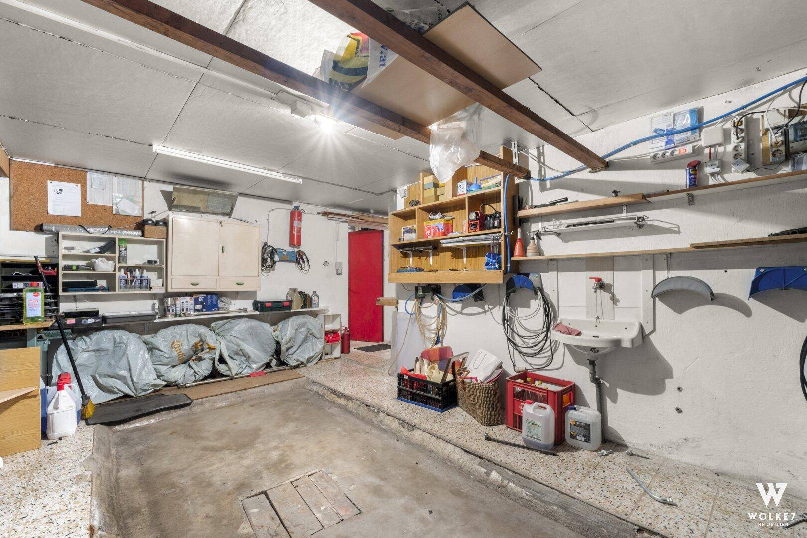 Werkstatt und Garage mit Waschbecken, Regalen und Werkzeugen.