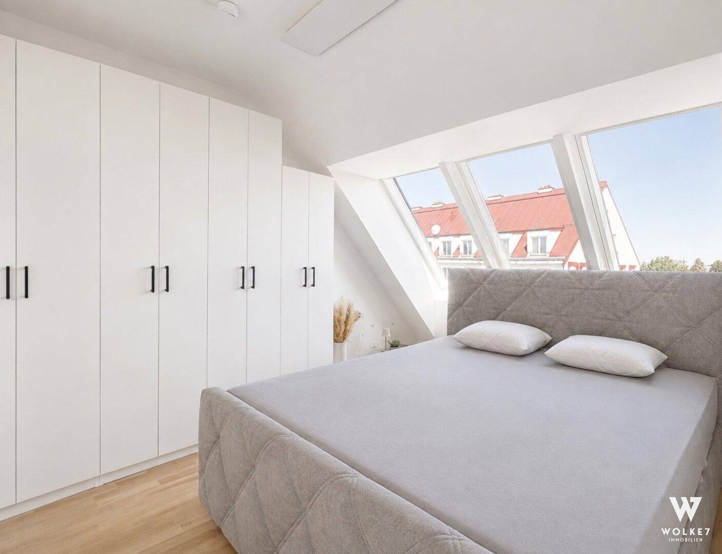 Helles Schlafzimmer im Dachgeschoss mit großen Dachfenstern und integrierten Kleiderschränken.