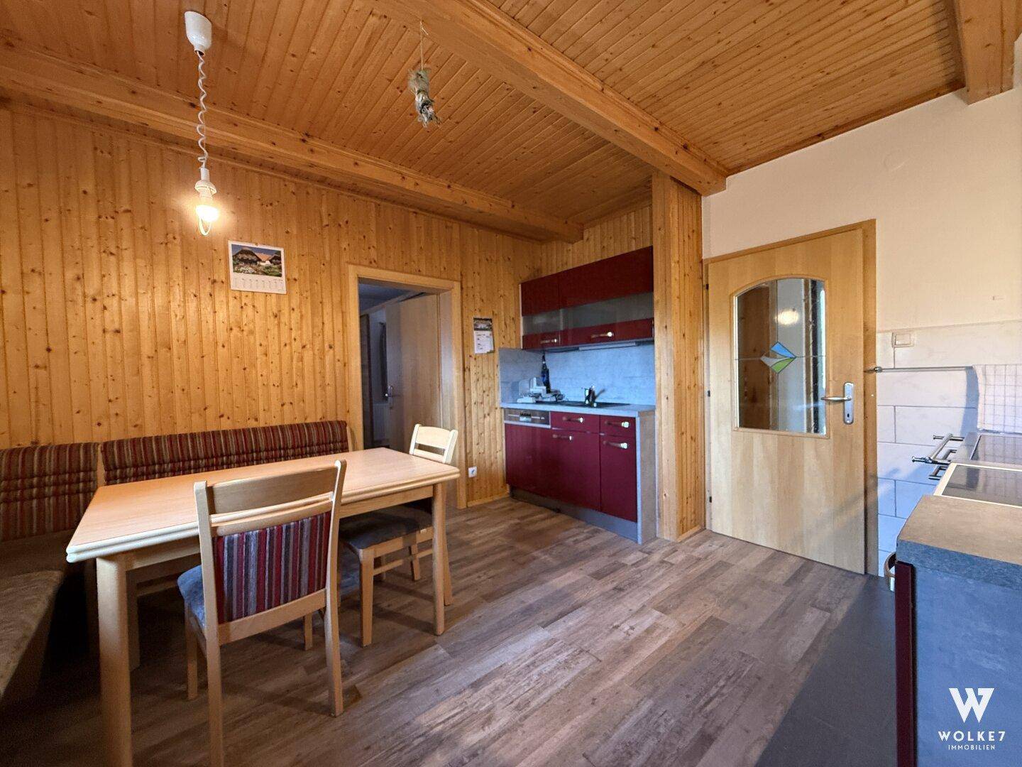 Rustikale Küche mit Holzwänden und Decke, Essbereich und kleiner Küchenzeile.