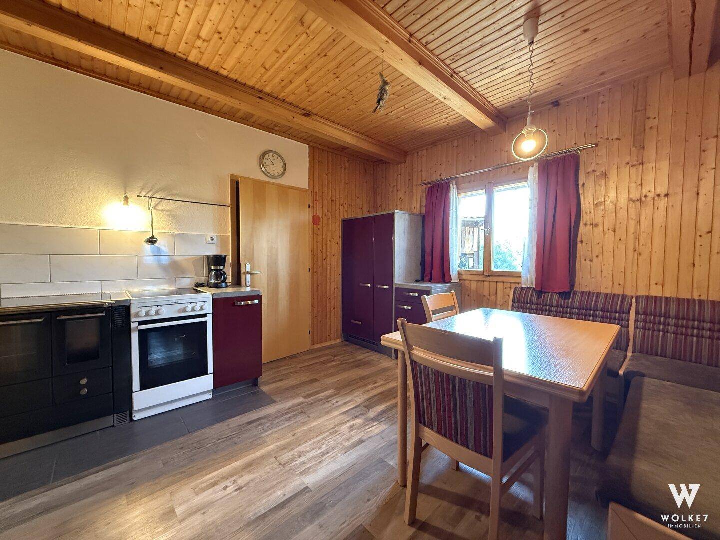 Gemütliche Küche mit Holzwänden, Essbereich und einfacher Küchenzeile.