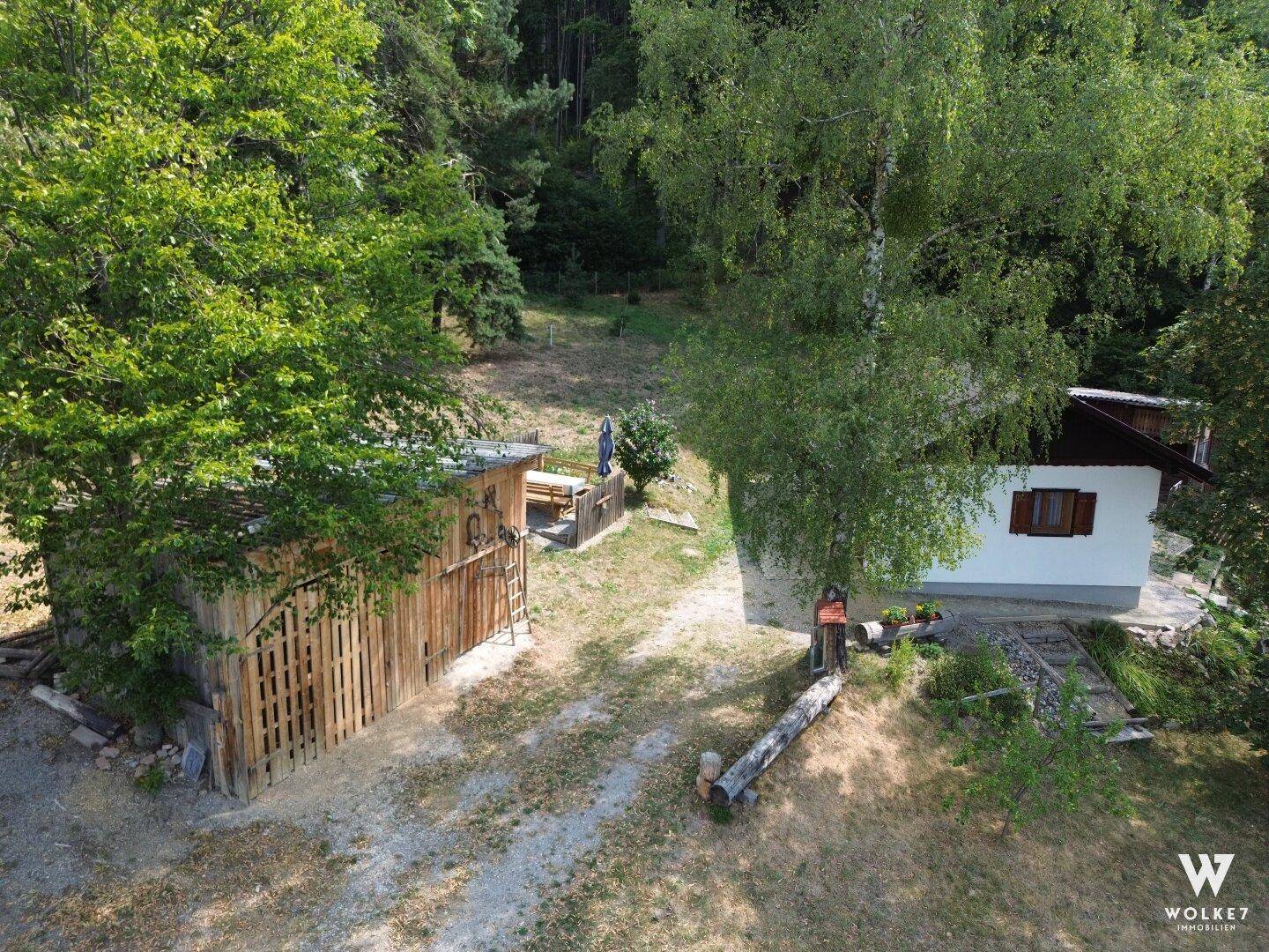 Luftaufnahme des Hauses und eines Nebengebäudes, umgeben von Bäumen und Natur.