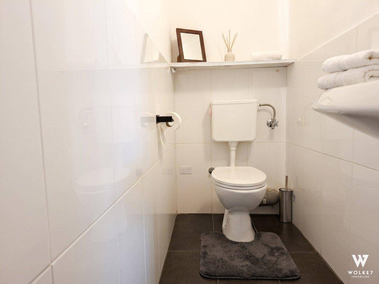 Kleines Gäste-WC mit weißen Fliesen und einfacher Ausstattung.