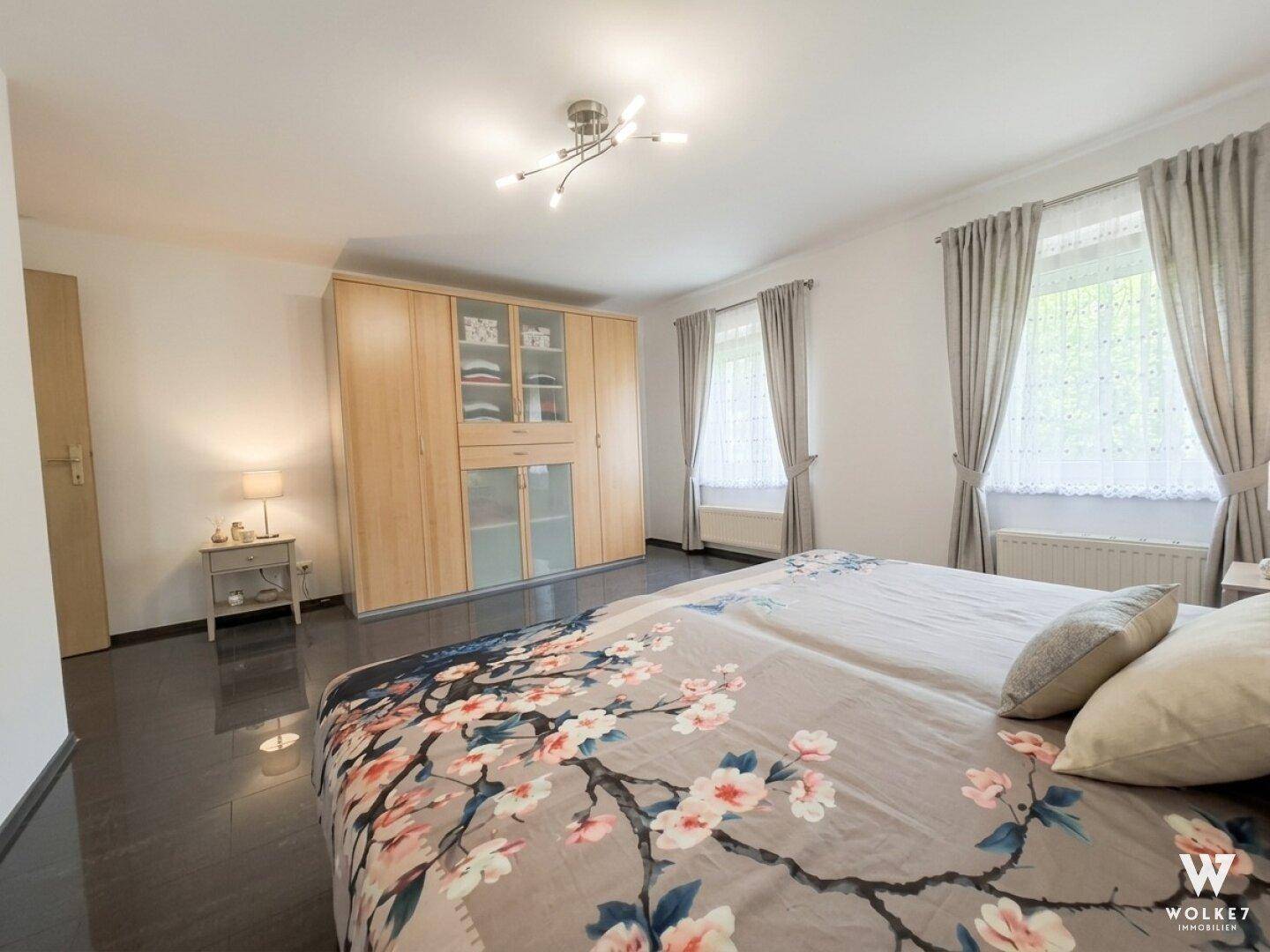 Geräumiges Schlafzimmer mit großem Kleiderschrank und floral gemustertem Bett.