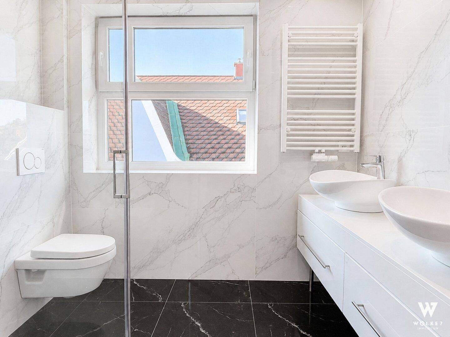 Modernes Badezimmer mit Marmorfliesen, Doppelwaschbecken und beheiztem Handtuchhalter.