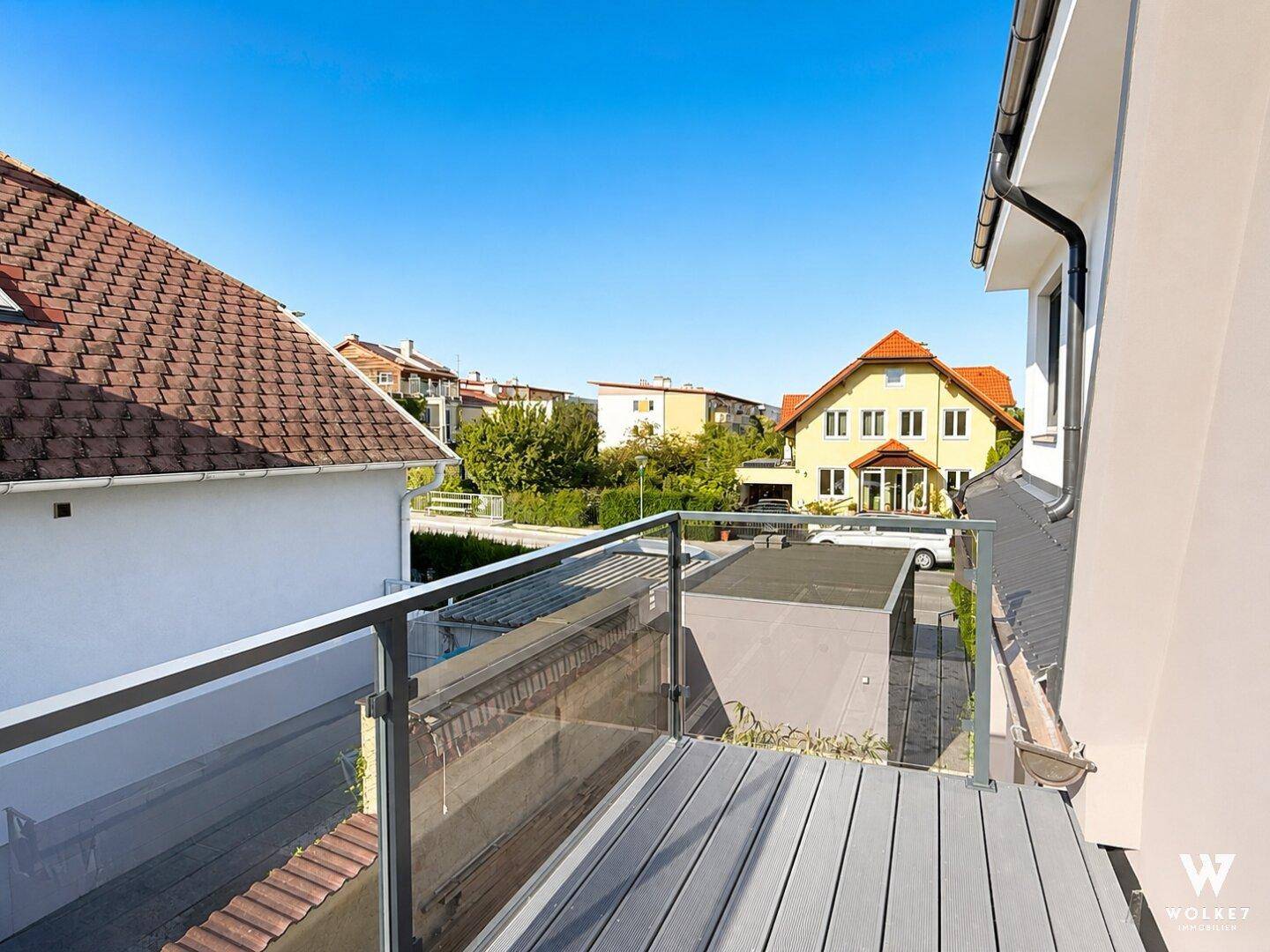Moderner Balkon mit Glasgeländer und Blick auf die umliegende Wohngegend.