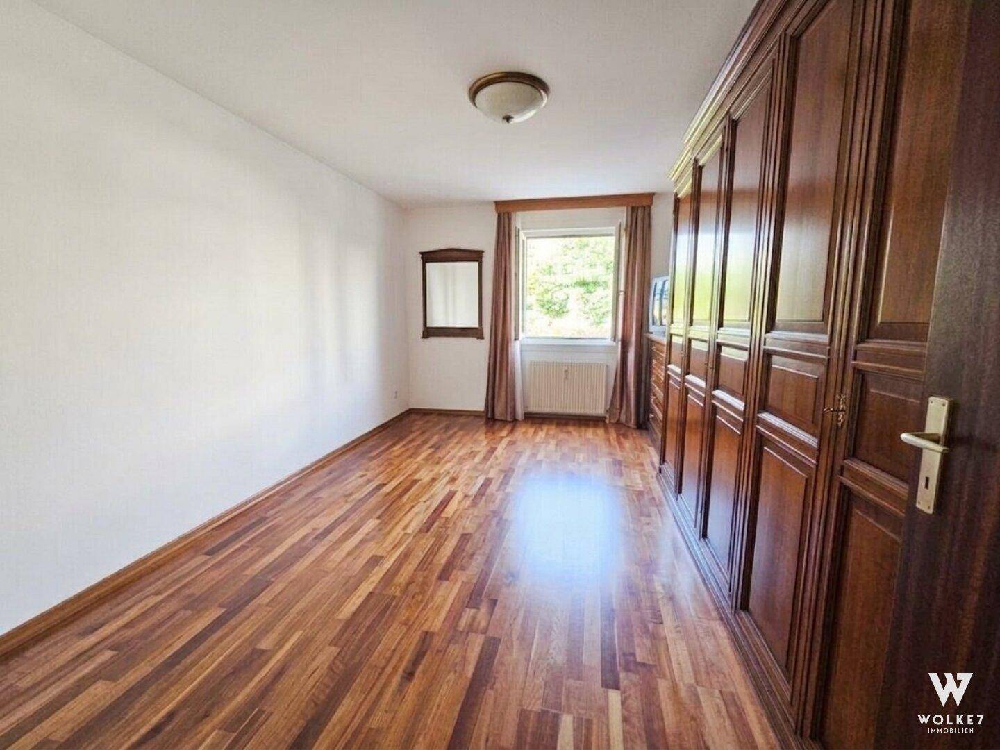 Helles Schlafzimmer mit Holzboden, weißen Wänden und einem großen Einbauschrank.