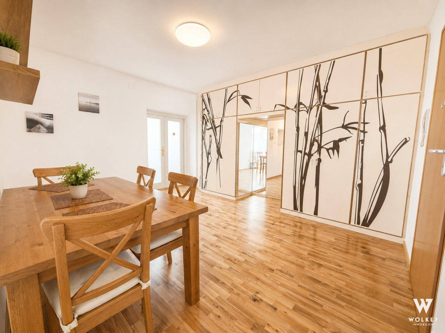 Essbereich mit Holztisch und Stühlen, Laminatboden und dekorativer Wandgestaltung.