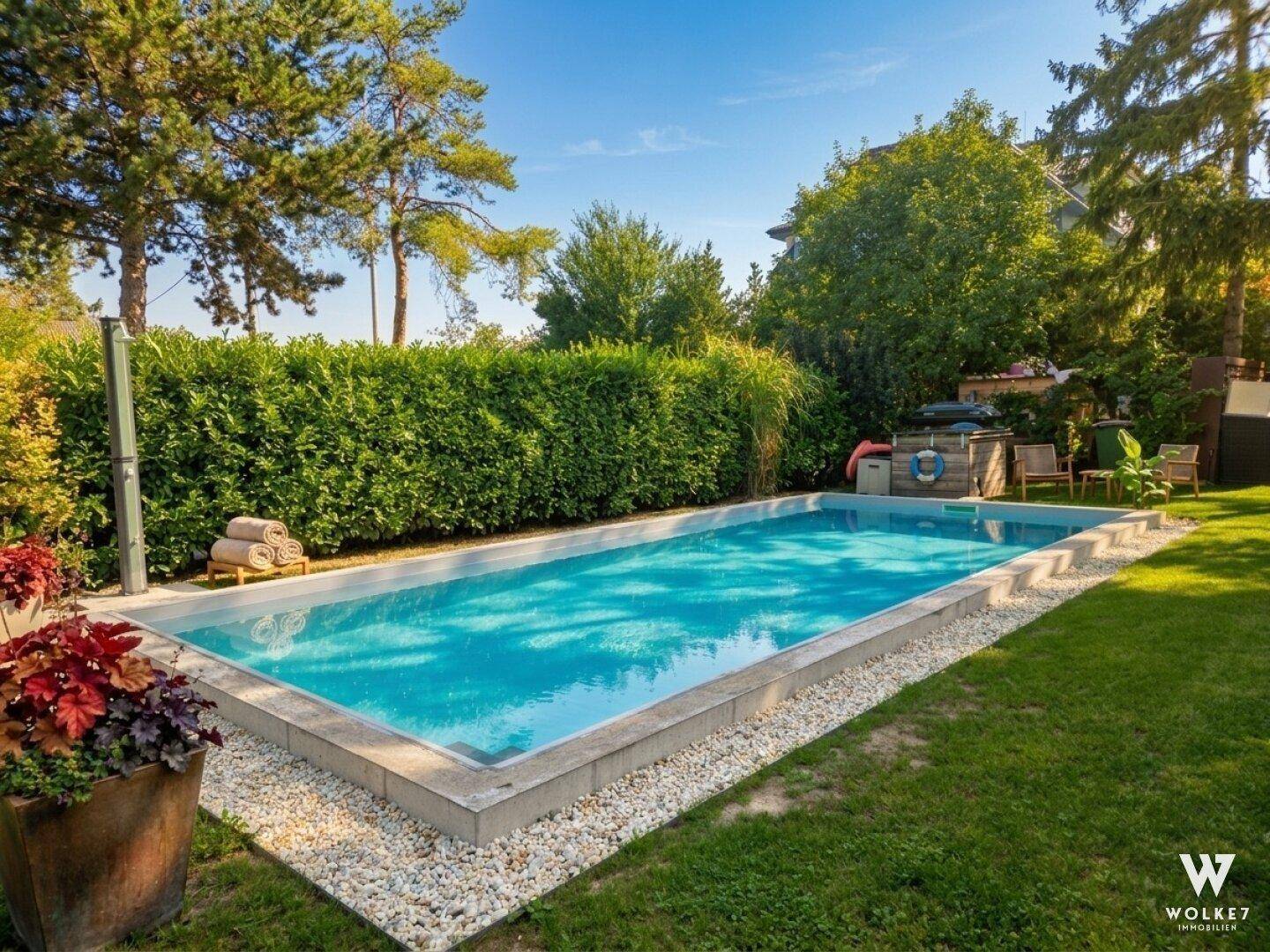Rechteckiger Swimmingpool im gepflegten Garten, umgeben von Kies und grünen Hecken.
