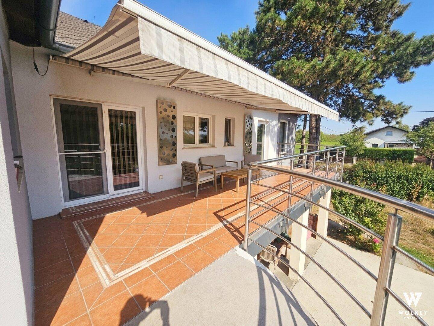 Geräumiger Balkon mit Markise und Metallgeländer, bietet Platz für eine kleine Sitzecke.