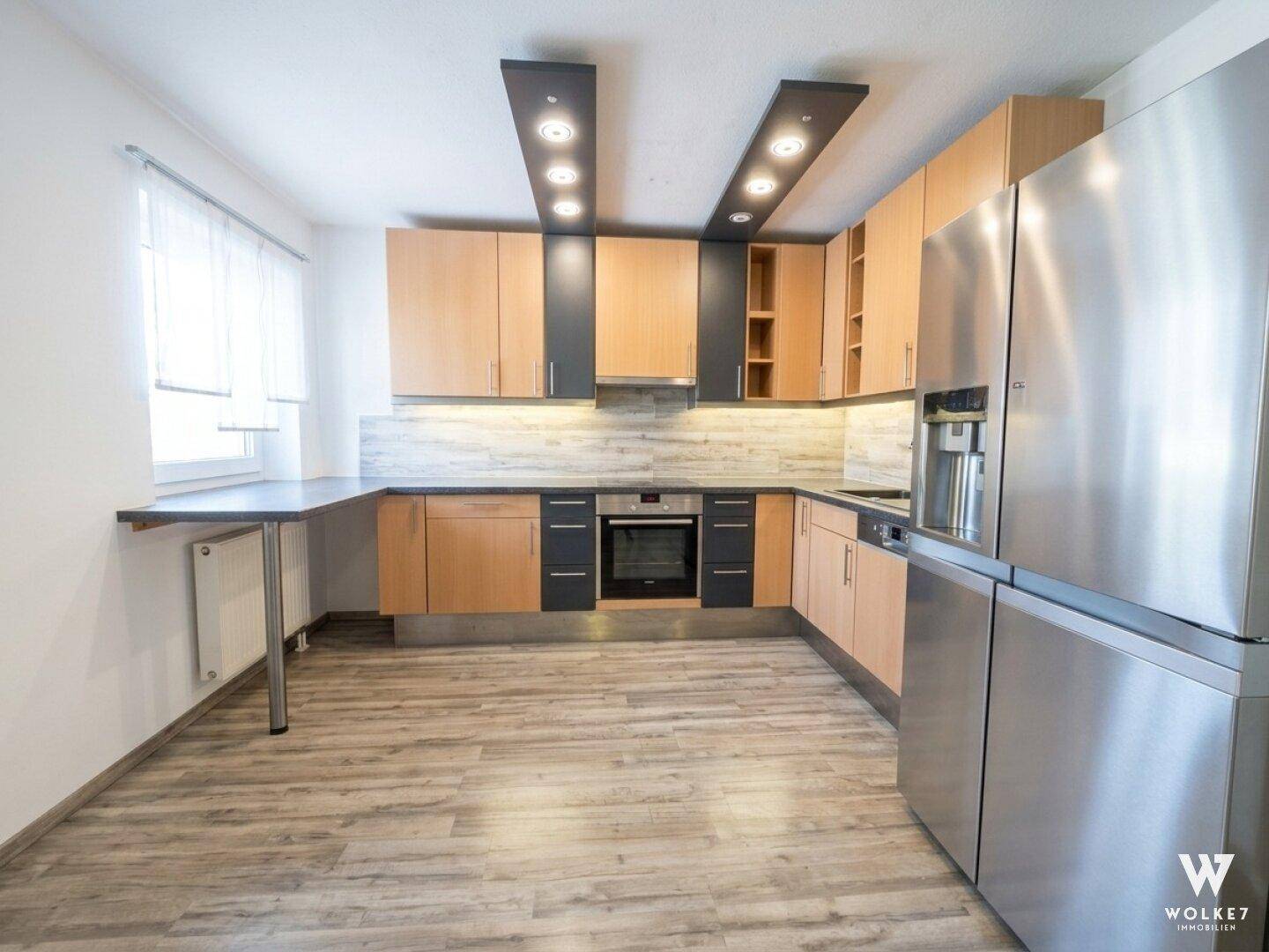 Moderne Küche mit Holz- und Anthrazitfronten, integrierten Geräten und viel Arbeitsfläche.