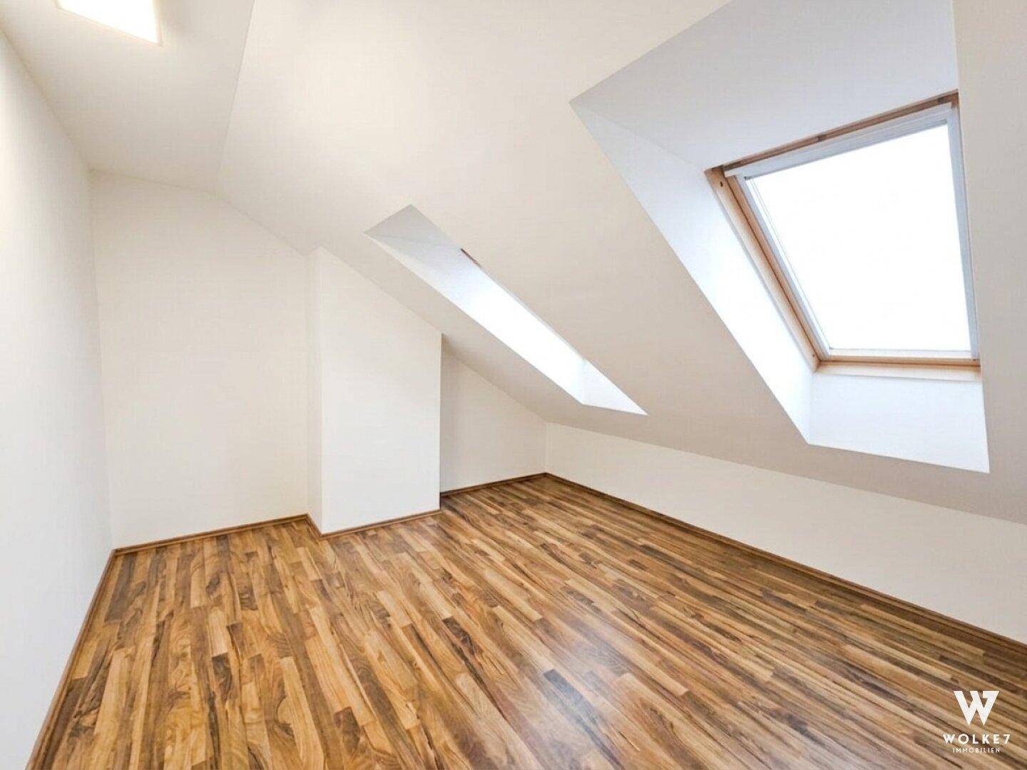 Geräumiges Dachzimmer mit mehreren Dachfenstern, ideal als Schlaf- oder Arbeitsbereich.