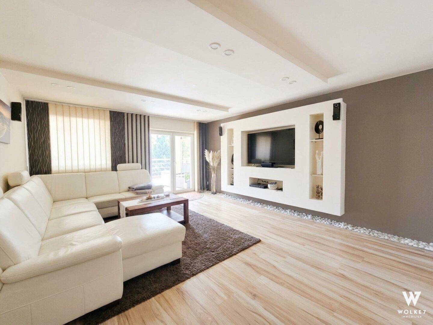Helles Wohnzimmer mit modernem Design, großem Ecksofa und Holzboden.