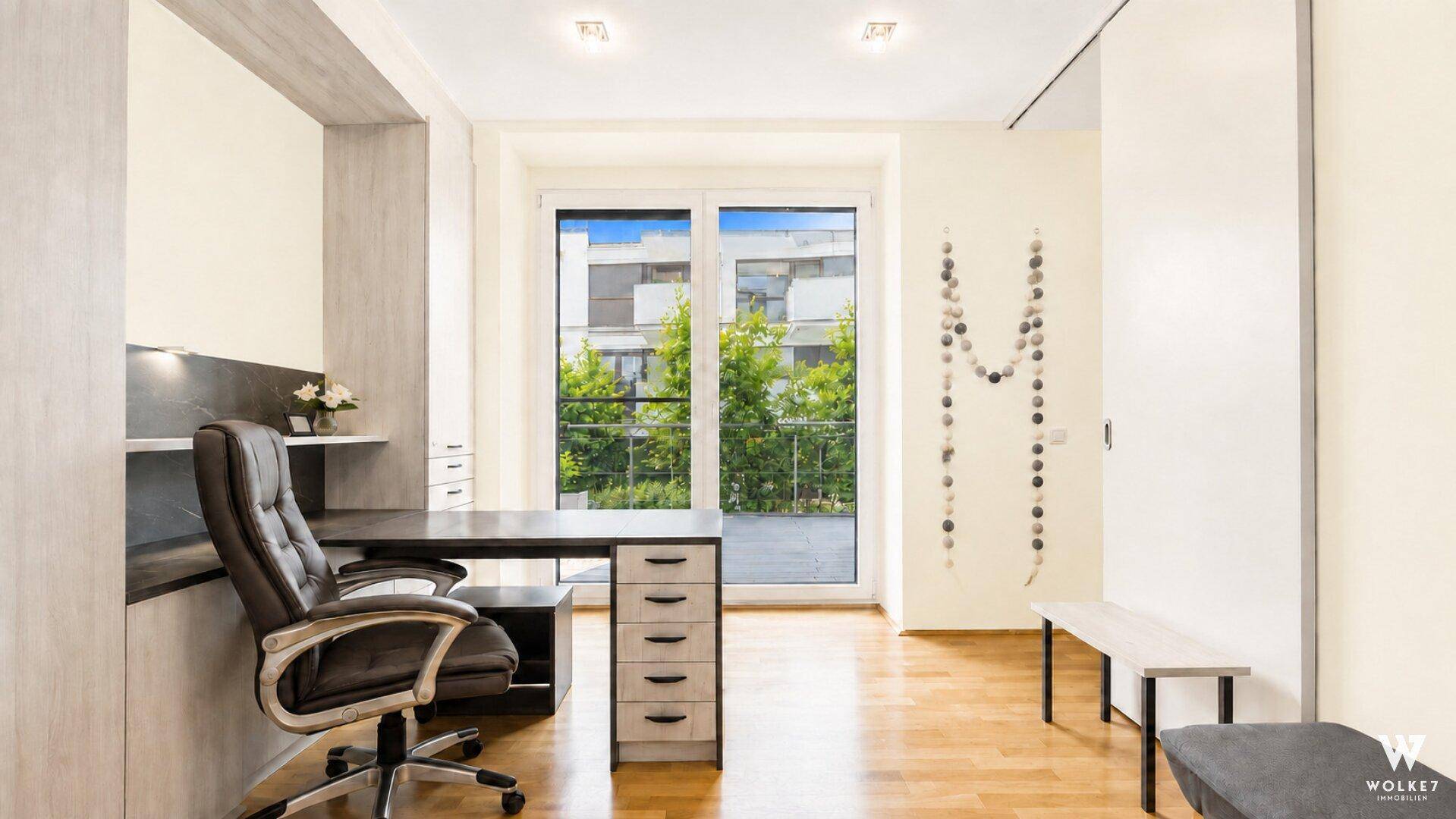 Helles Arbeitszimmer mit modernem Schreibtisch, Bürostuhl und Zugang zu einem kleinen Balkon.