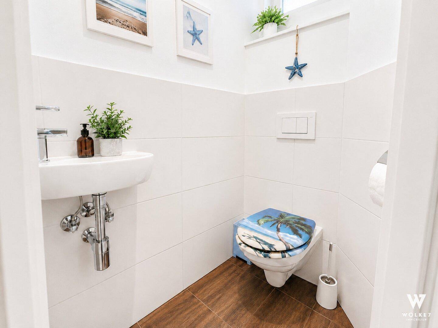 Kleines Gäste-WC mit modernem Waschbecken und dekorativer Toilettenbrille in maritimen Stil.