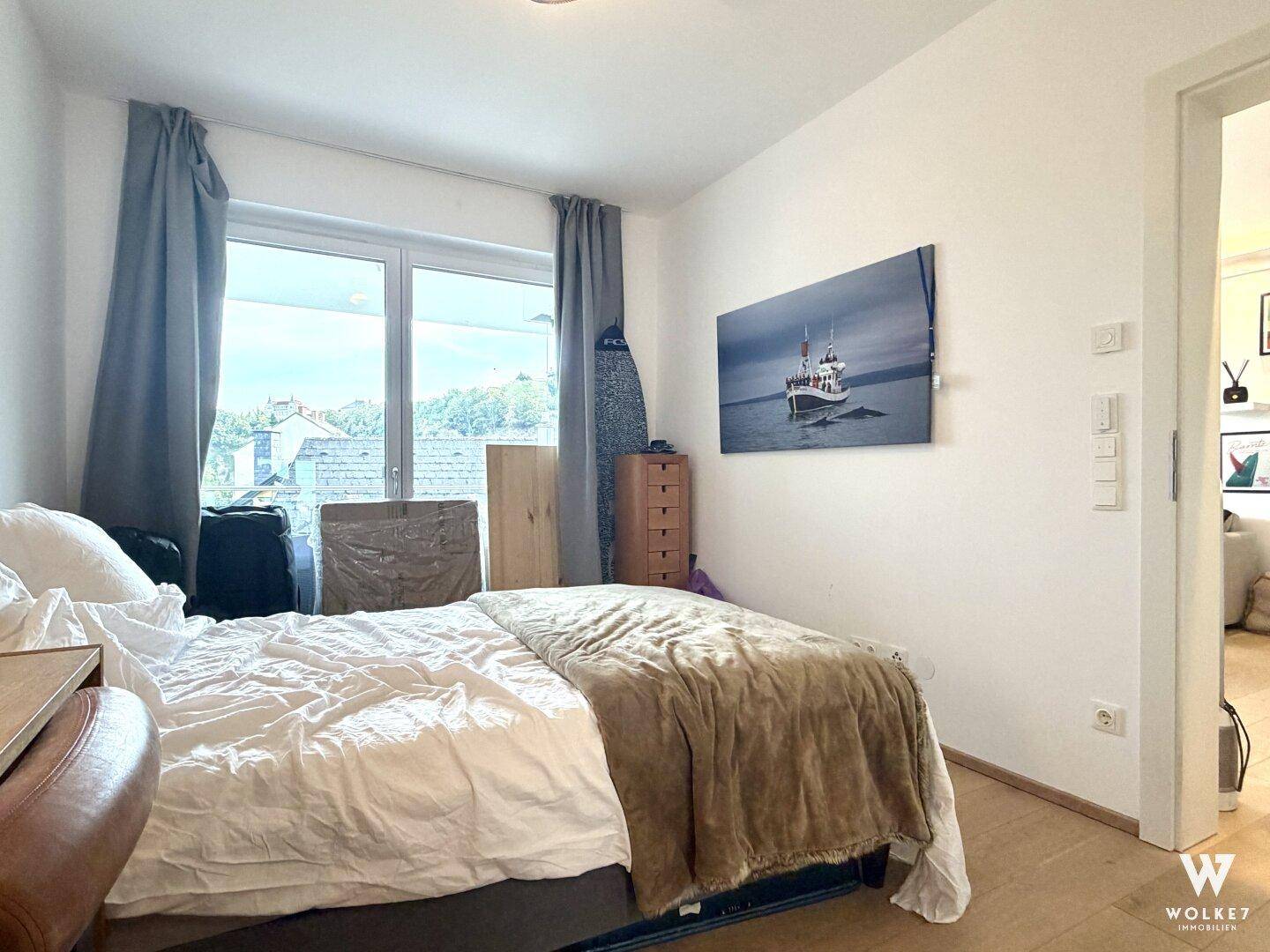 Gemütliches Schlafzimmer mit Holzboden, großem Fenster und Blick auf die Umgebung.