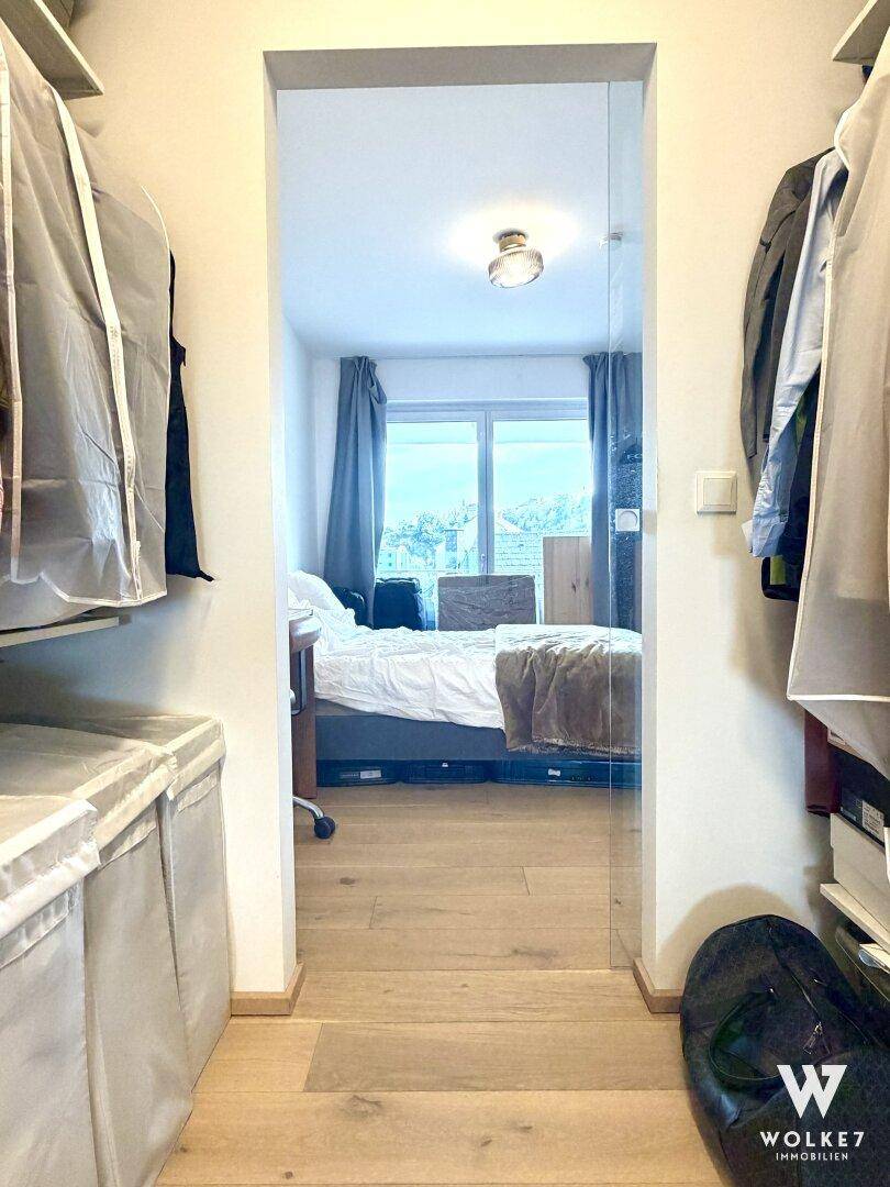 Praktischer begehbarer Kleiderschrank mit Stauraum, der zu einem Schlafzimmer führt.