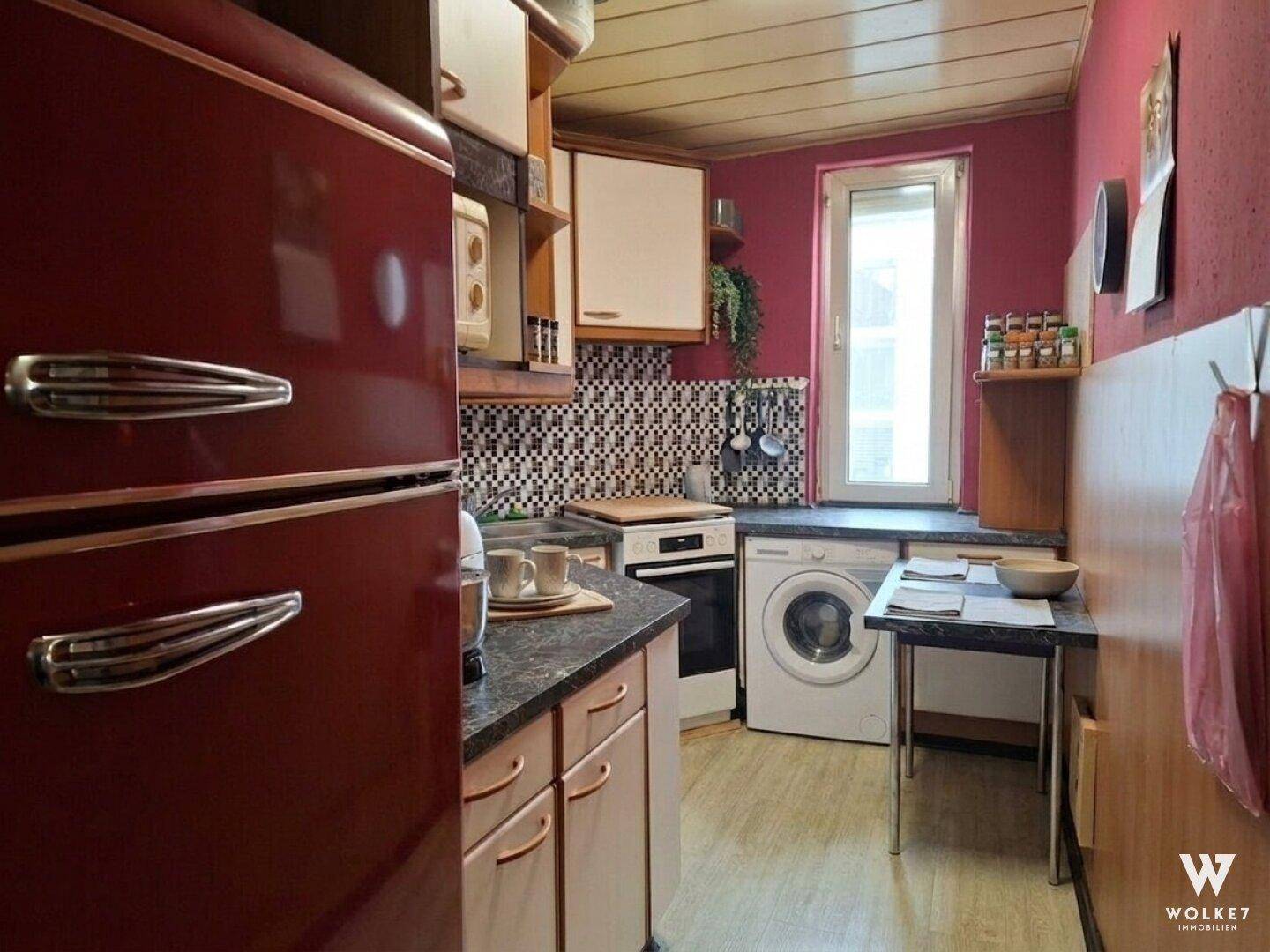 Küche mit retro-rotem Kühlschrank, Waschmaschine und Holzdeckenverkleidung.