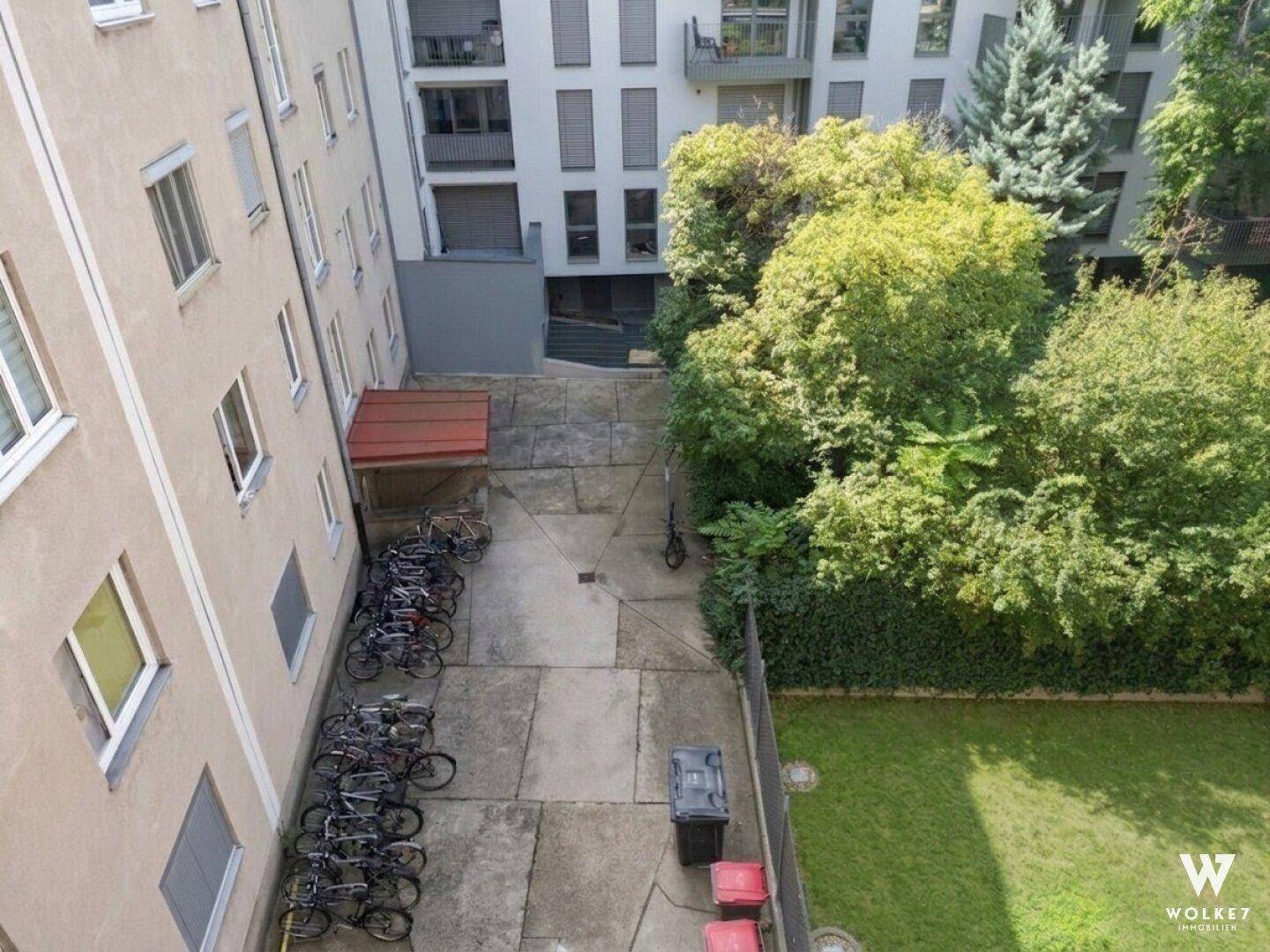 Innenhof mit Fahrradabstellplätzen, Grünfläche und umliegenden Gebäuden.