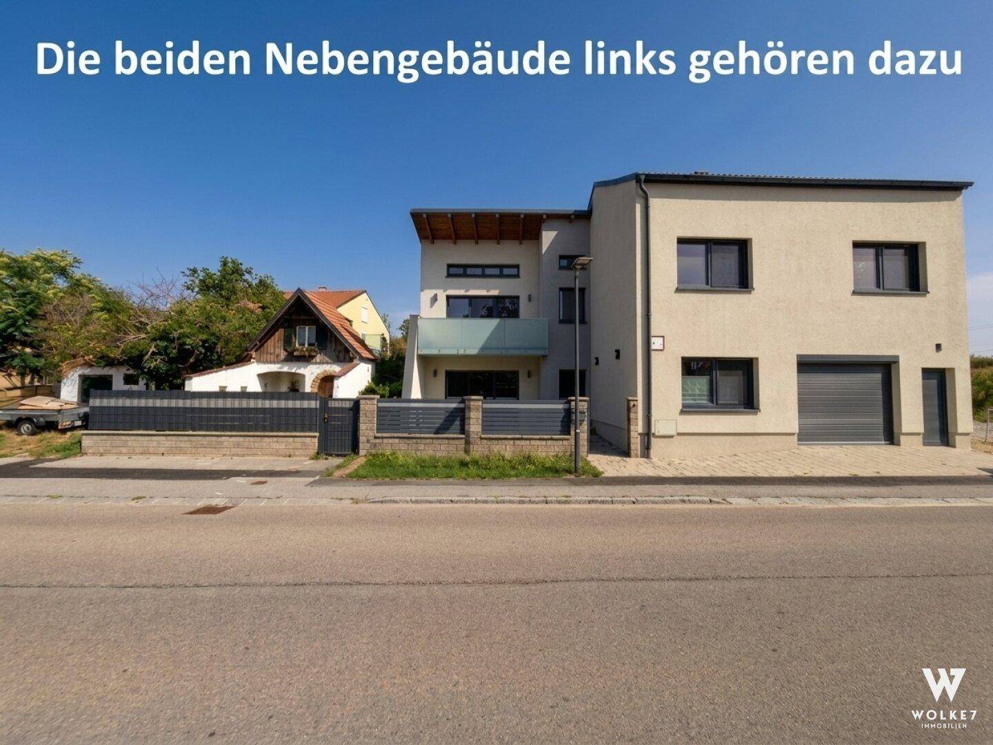 Gesamtansicht des modernen Hauses mit angrenzenden Nebengebäuden und Vorgarten.