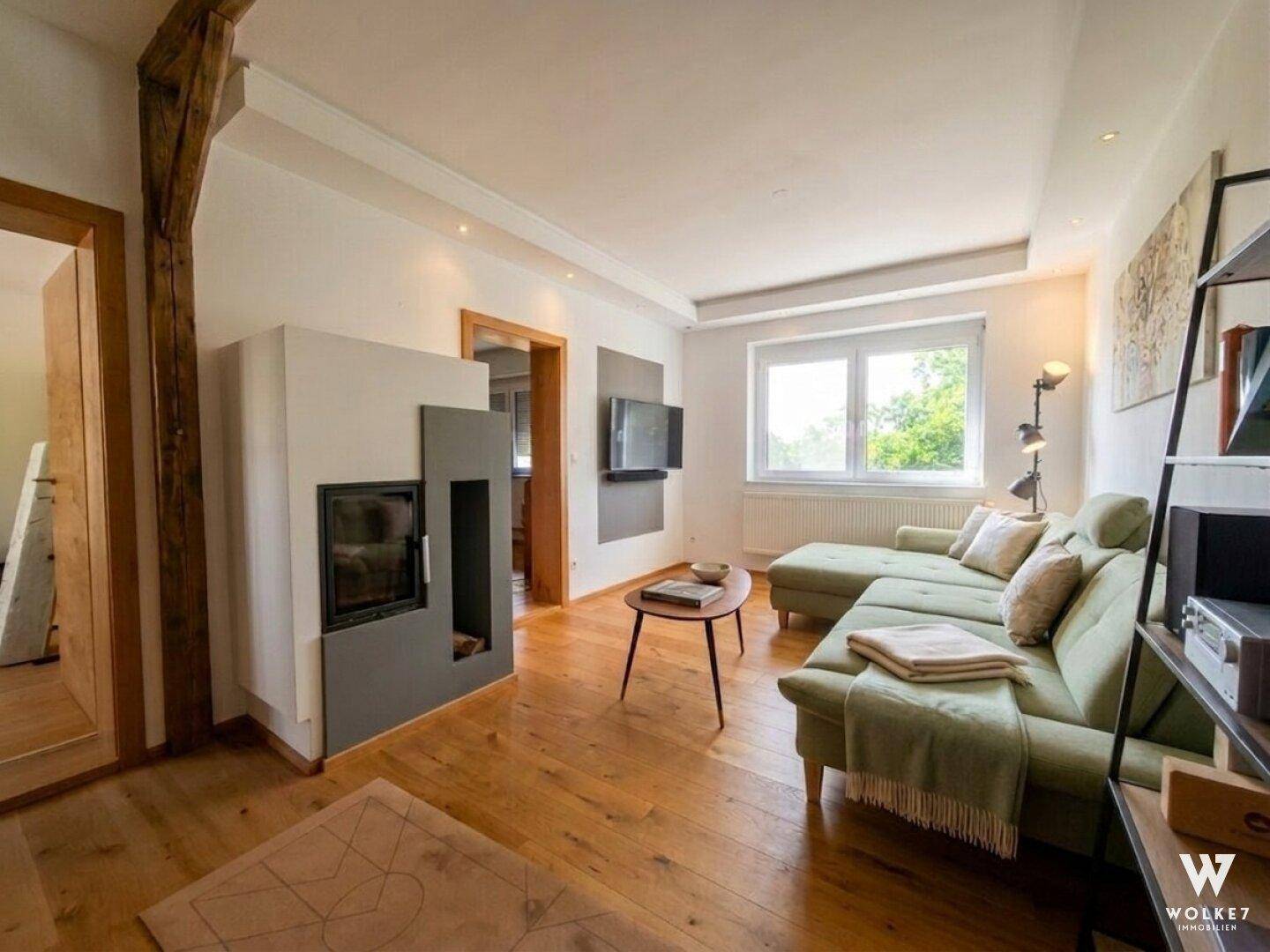 Gemütliches Wohnzimmer mit modernem Kamin, bequemer Couch und Blick ins Grüne.