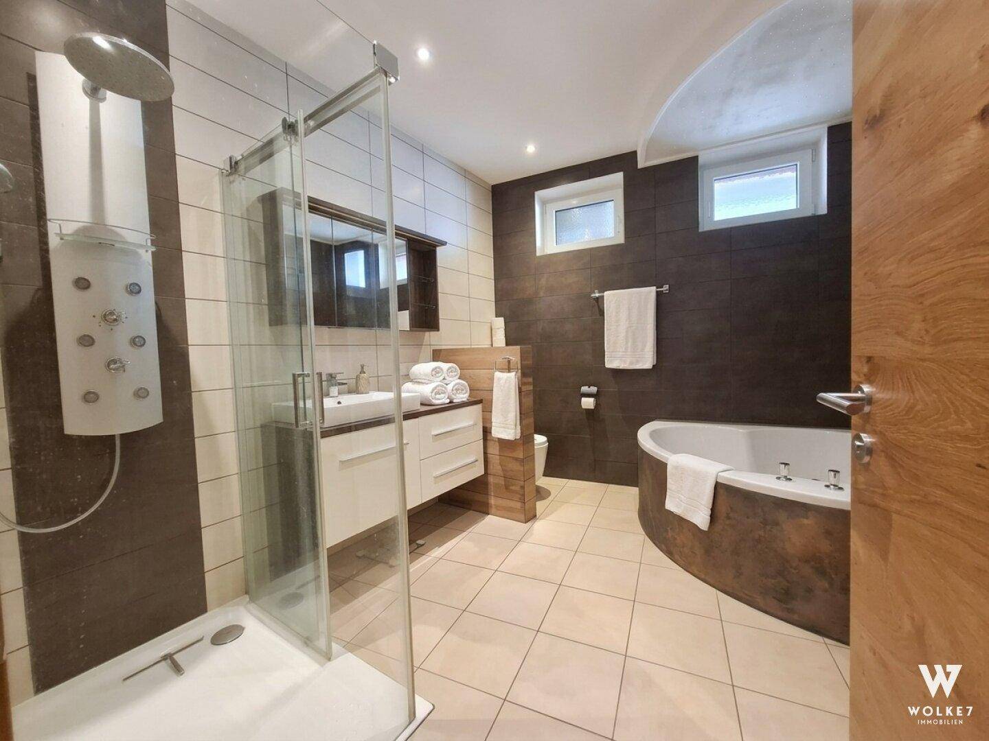 Modernes Badezimmer mit begehbarer Dusche, Doppelwaschbecken und Eckbadewanne.