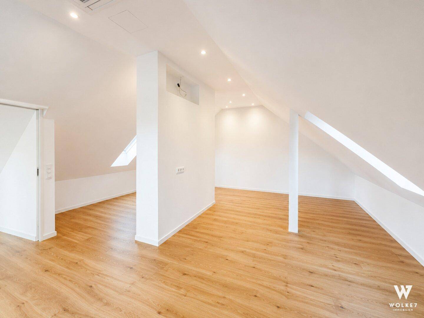 Geräumiger Dachboden mit Holzboden, schrägen Wänden und Dachfenstern, bereit zum Ausbau.