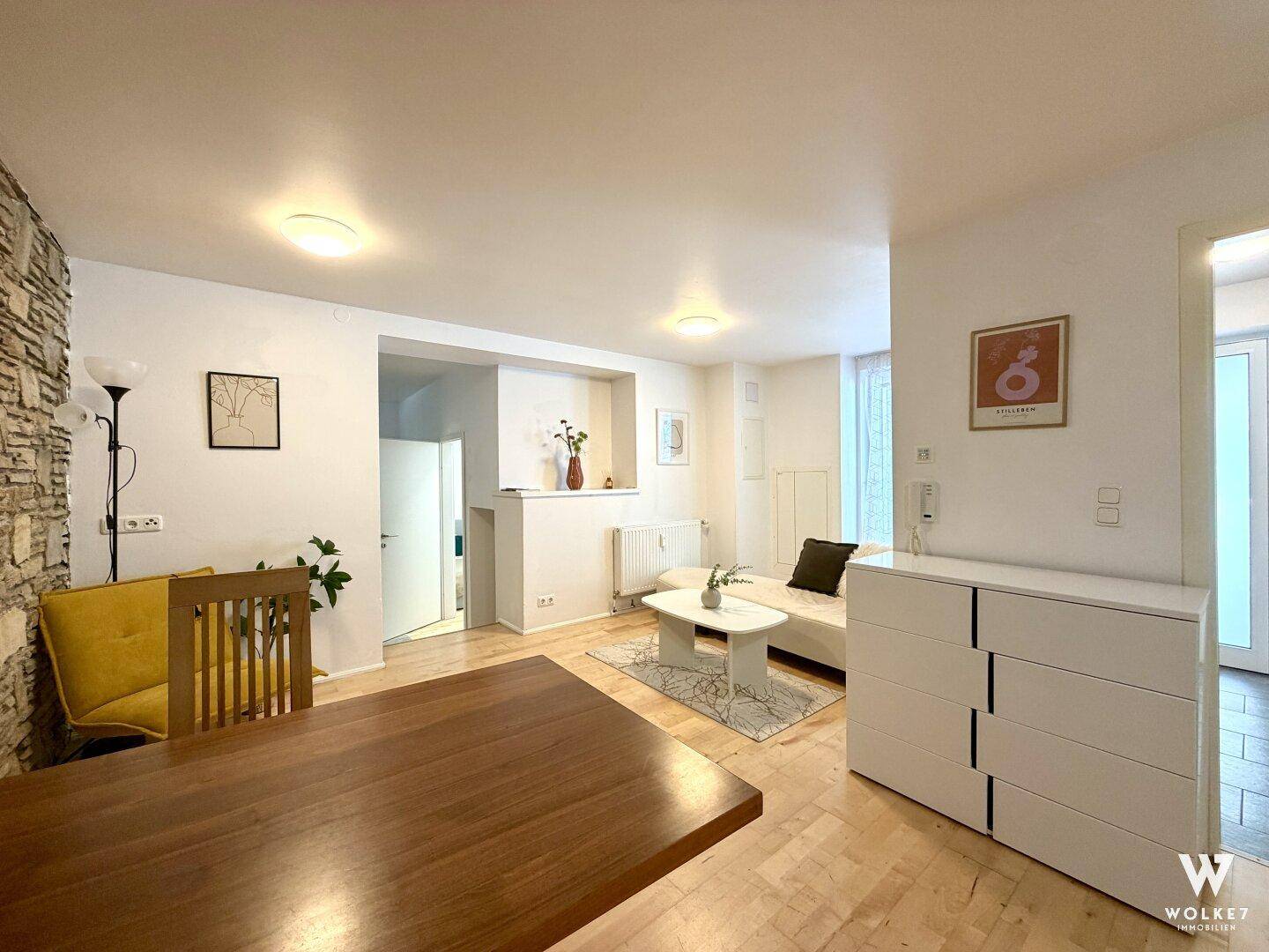 Geräumiger Wohn-Essbereich mit Holzboden, Esstisch und einer Wand mit Steinverkleidung.