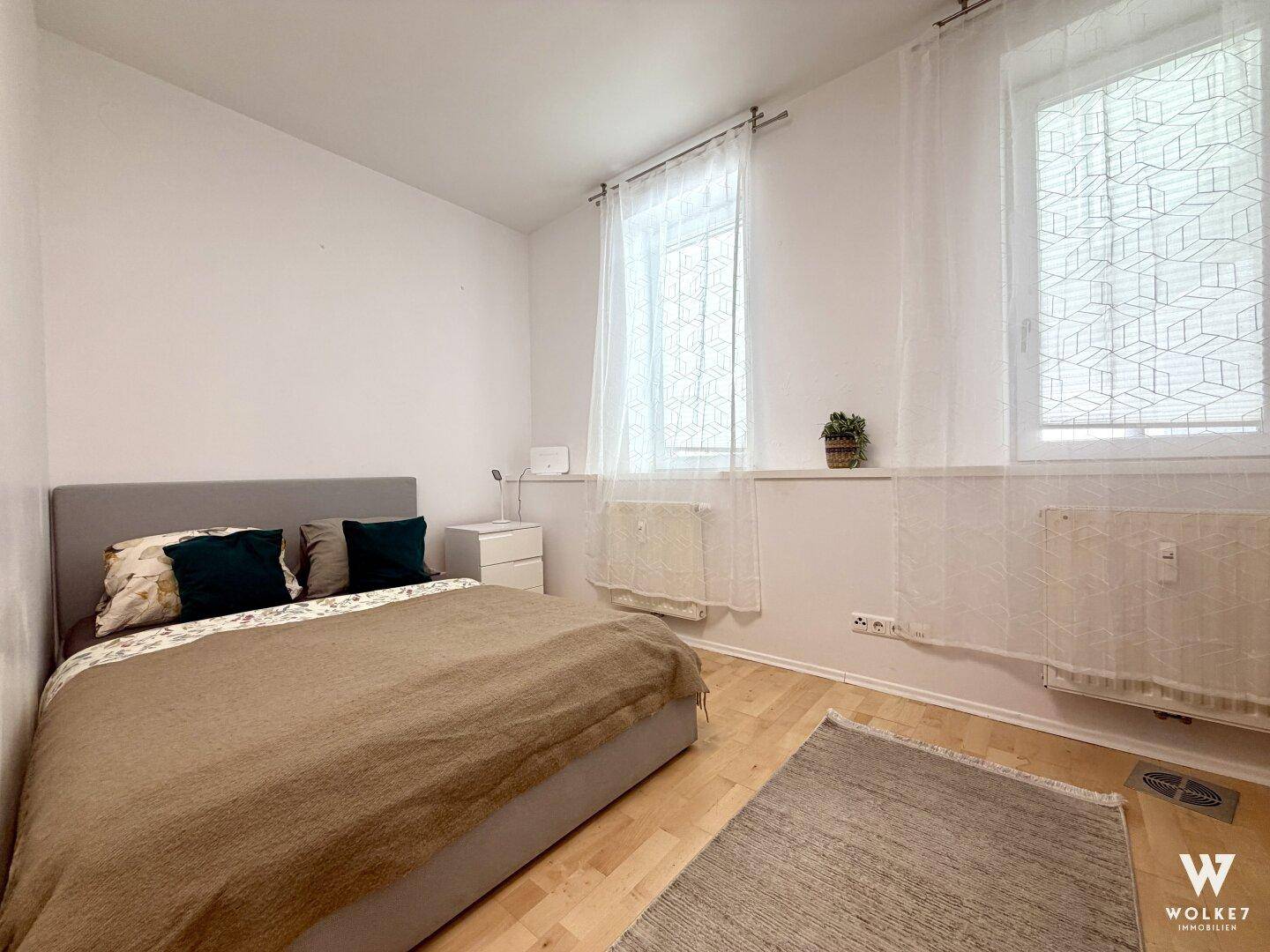 Gemütliches Schlafzimmer mit Doppelbett, Nachttisch und hellem Holzboden.