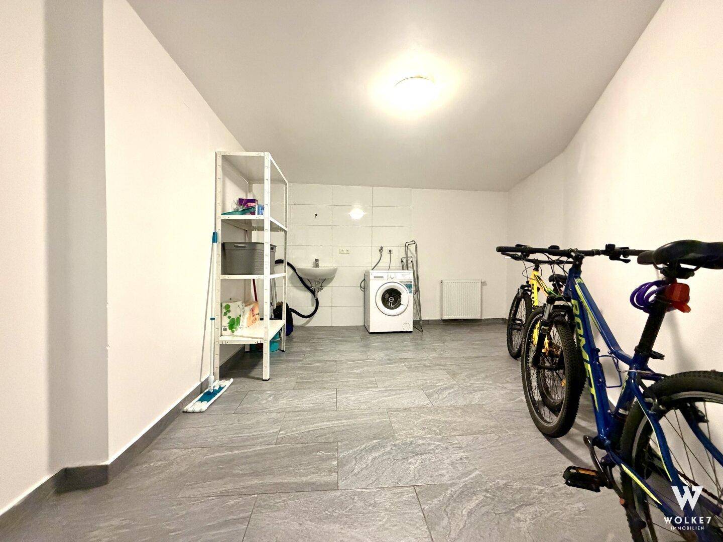 Geräumiger Hauswirtschaftsraum mit Waschmaschine, Spülbecken und Abstellmöglichkeiten.