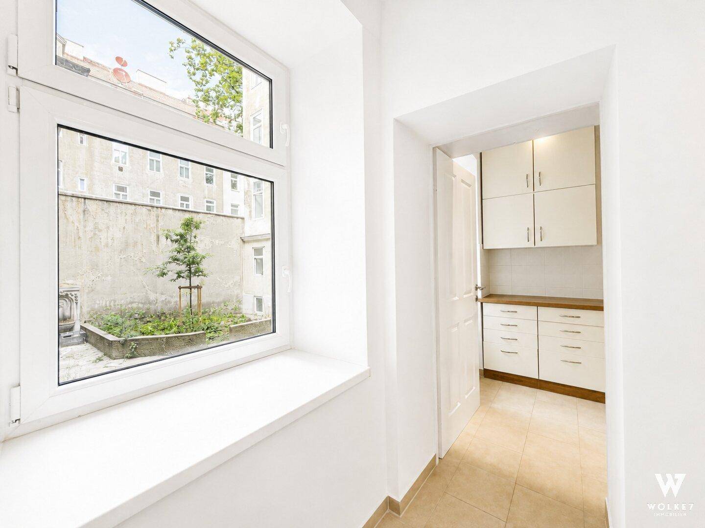 Heller Flur mit Fenster zum Innenhof und Blick in die kleine Küche.