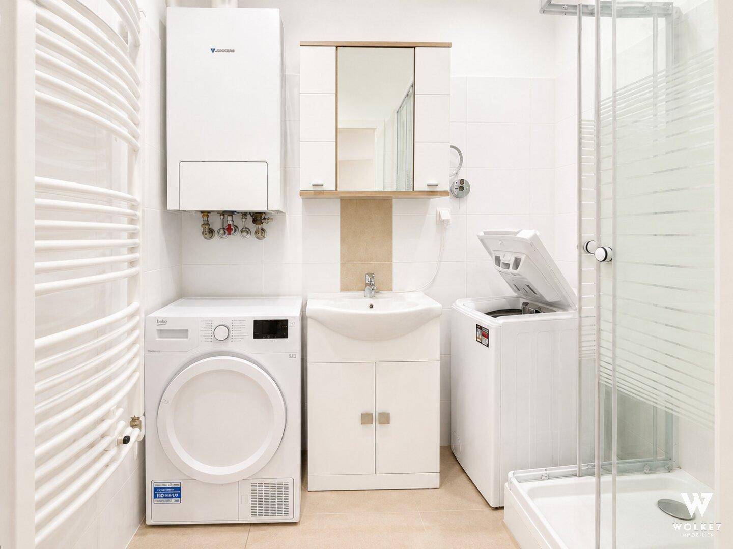 Modernes Badezimmer mit Dusche, Waschmaschine, Trockner und Heizkörper.